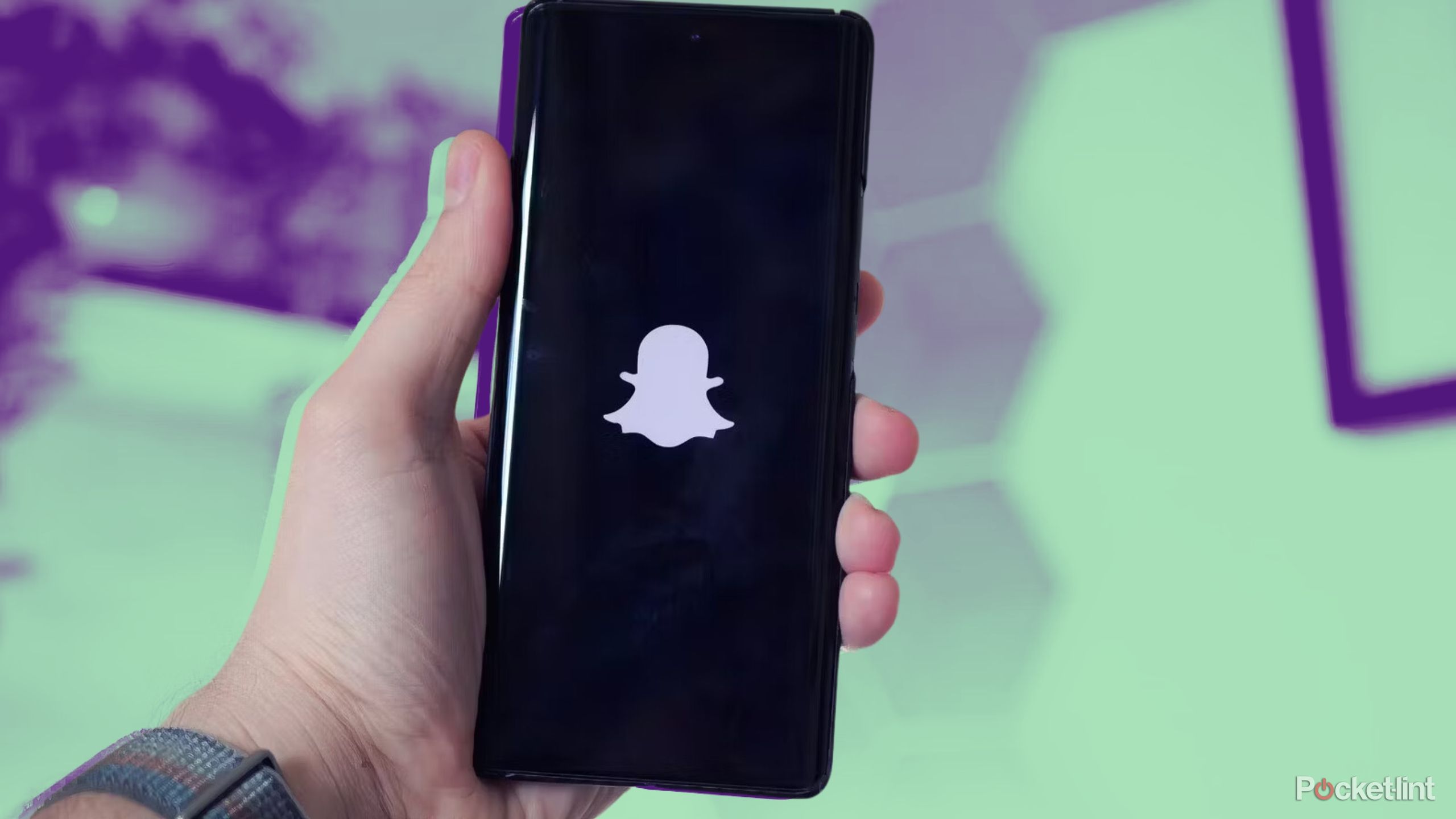 hand holding phone running snapchat app on colored background