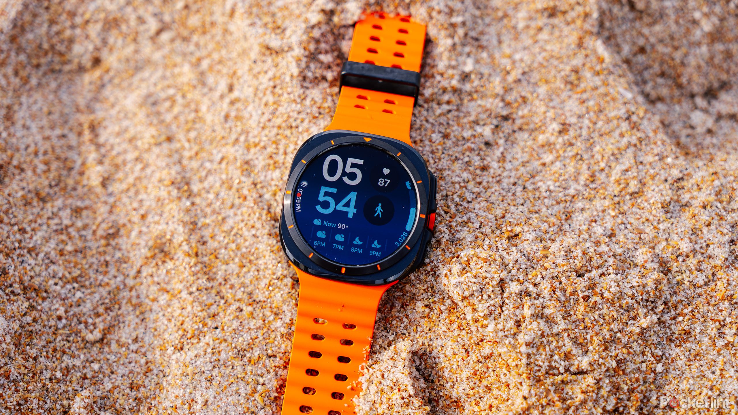 The Samsung Galaxy Watch Ultra sits in sand. 