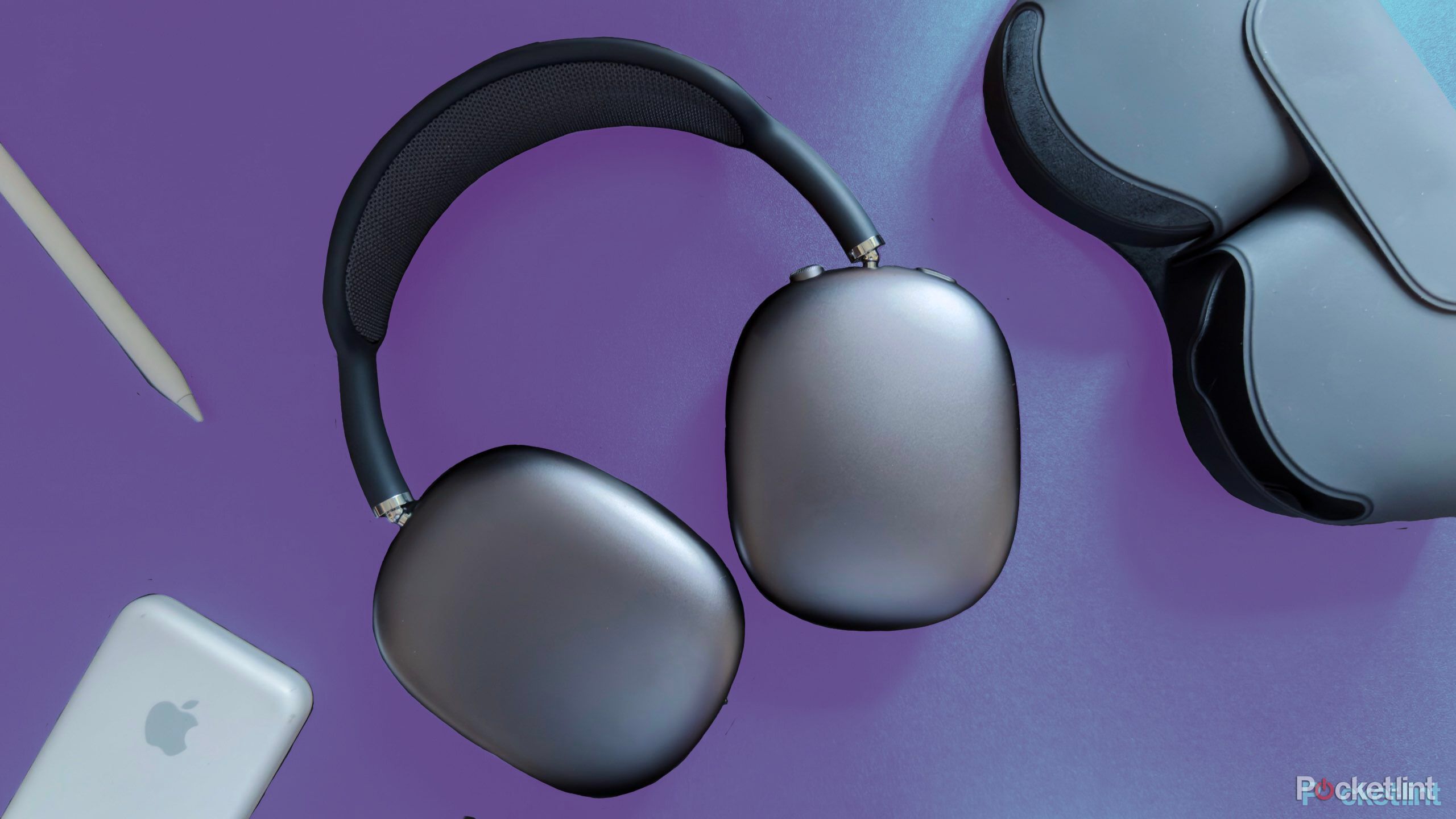 AirPods Max on a surface next to the smart case, an Apple Pencil, and an iPhone.