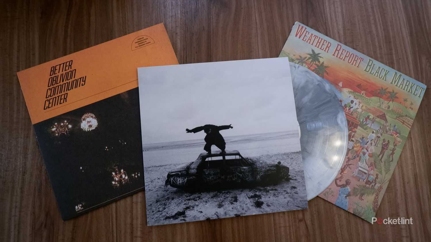 Three records in their jackets on the floor, from left to right: Better Oblivion Community Center's self-titled record, The 1975's Being Funny In A Foreign Language, with the record peeking out the right side, and Weather Report's Black Market.
