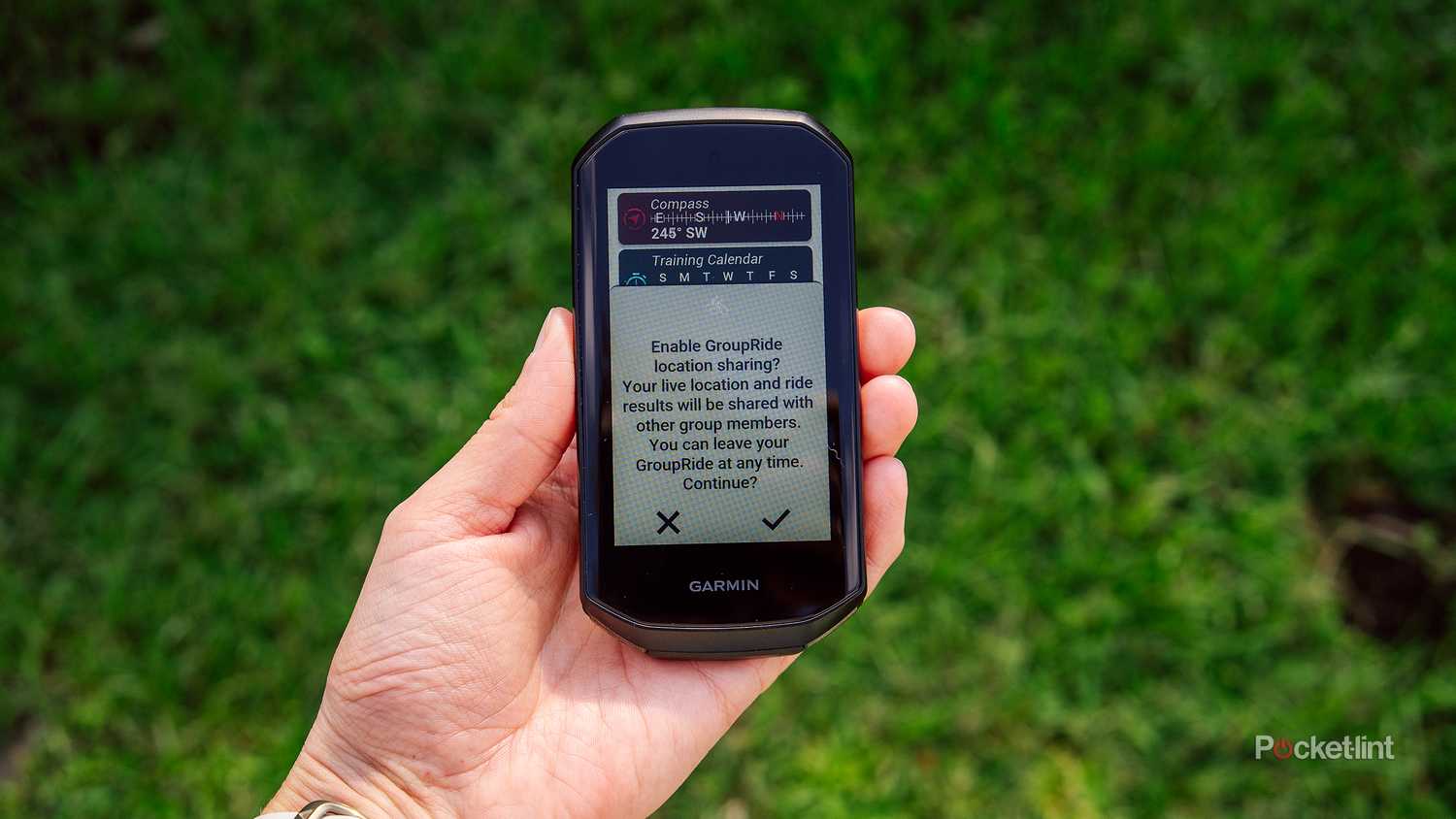 A hand holds the Garmin Edge 1050 with the GroupRide feature on the display. 