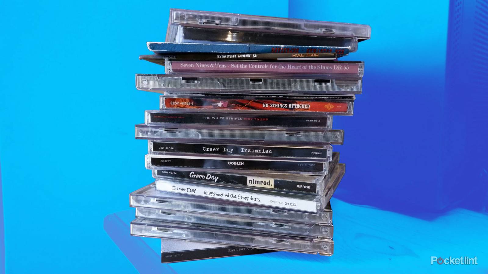 A stack of CDs in cases on a wooden desk