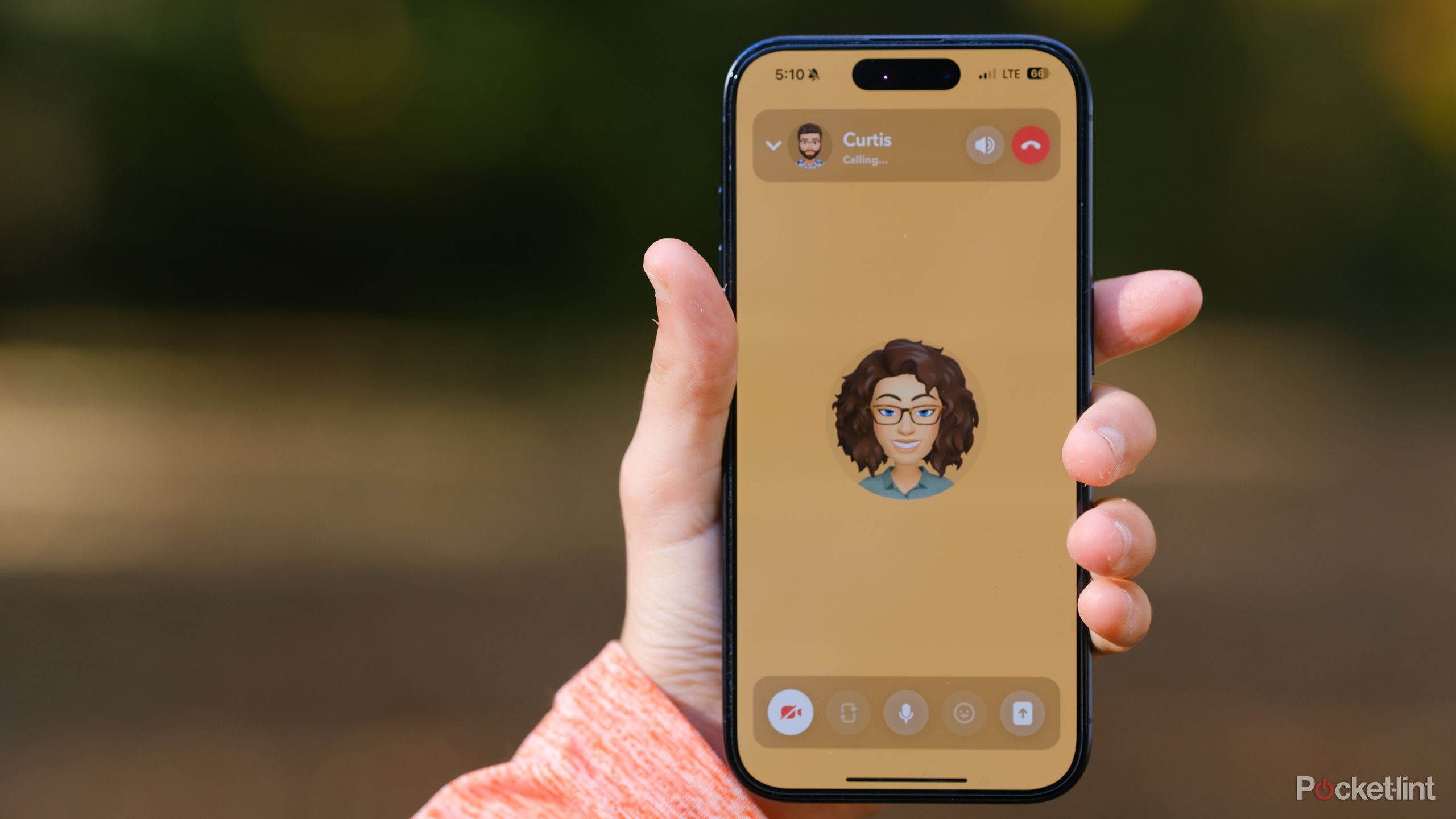 A hand holds an iPhone with a Snapchat video call.