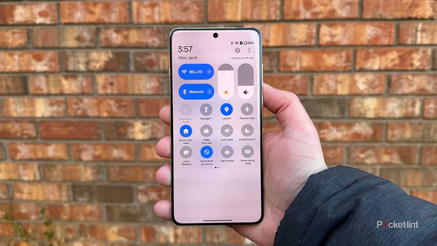OnePlus 13 in hand with the settings screen pulled up. 