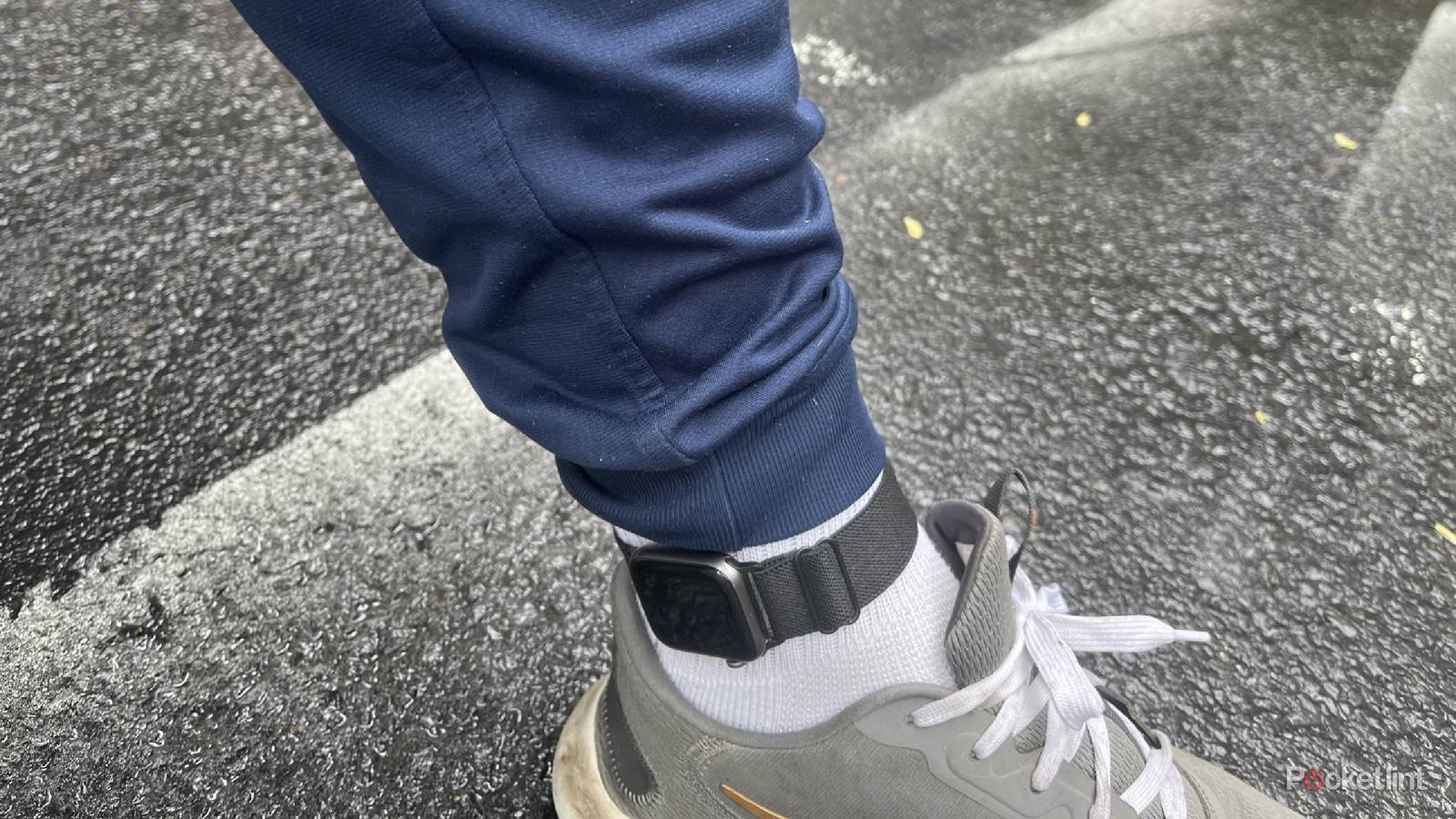An Apple Watch on an ankle outside on pavement