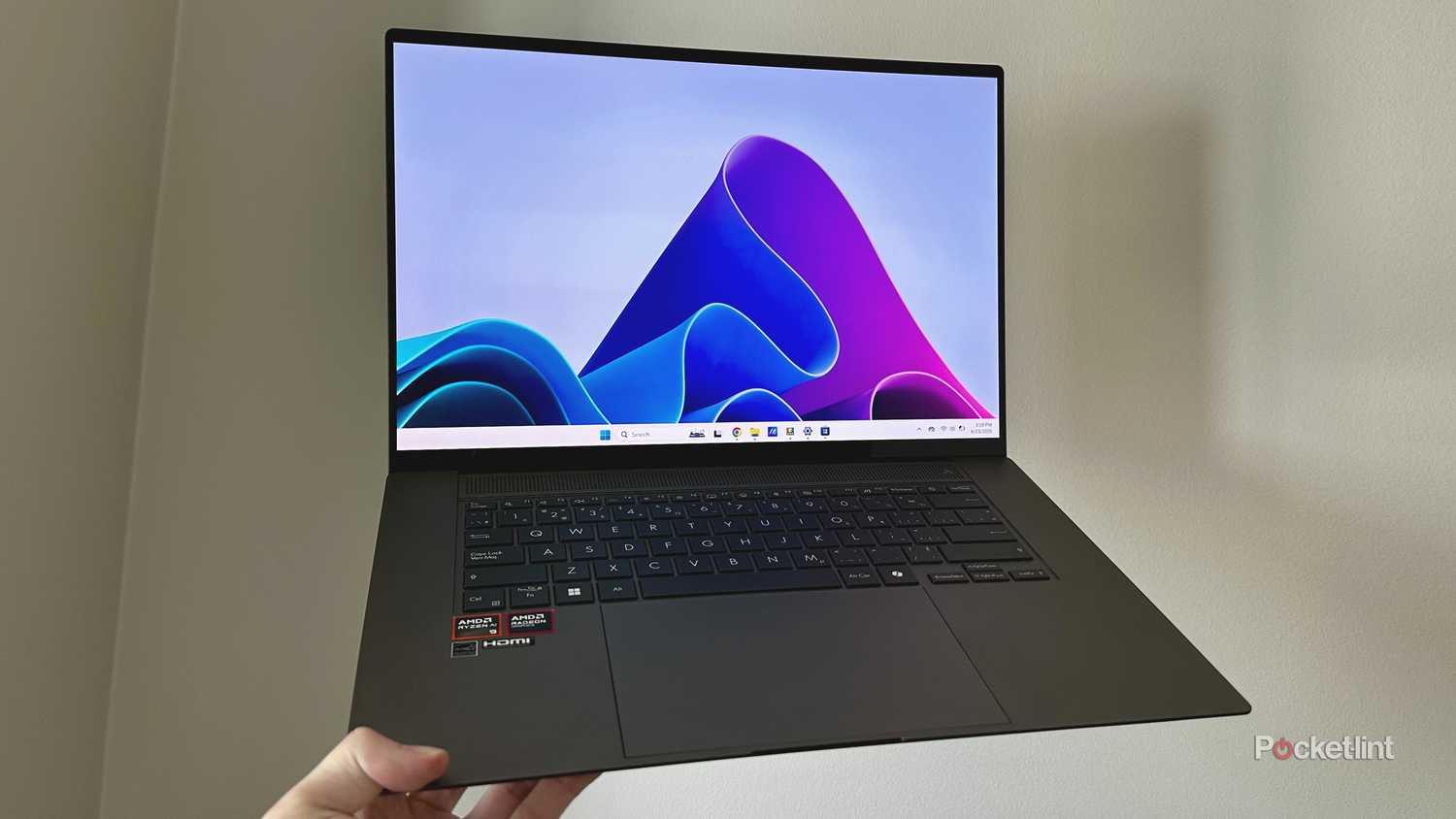 Asus Windows 11 laptop being held up in the air.