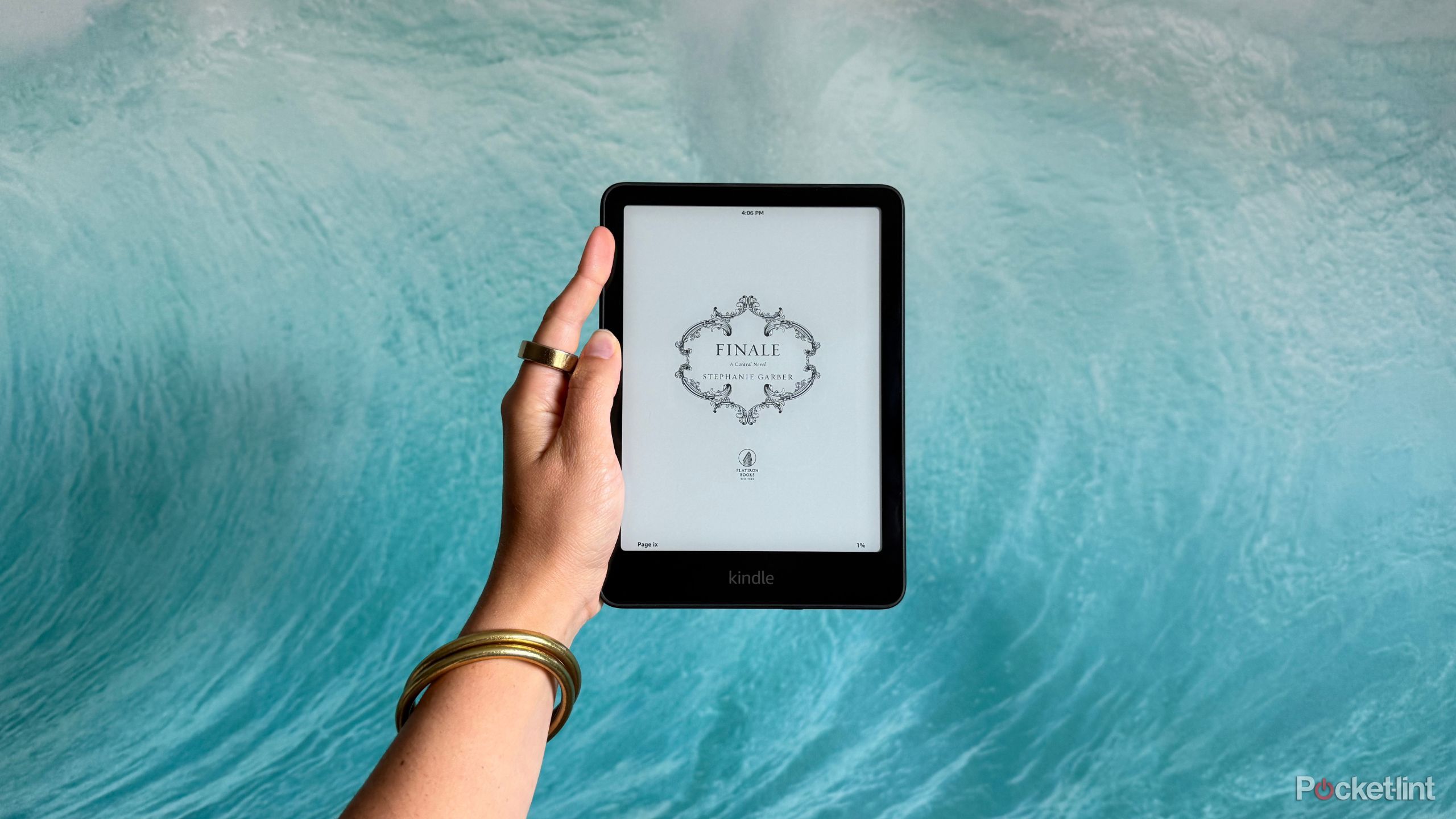 Holding a Kindle Paperwhite in front of a wave picture. 