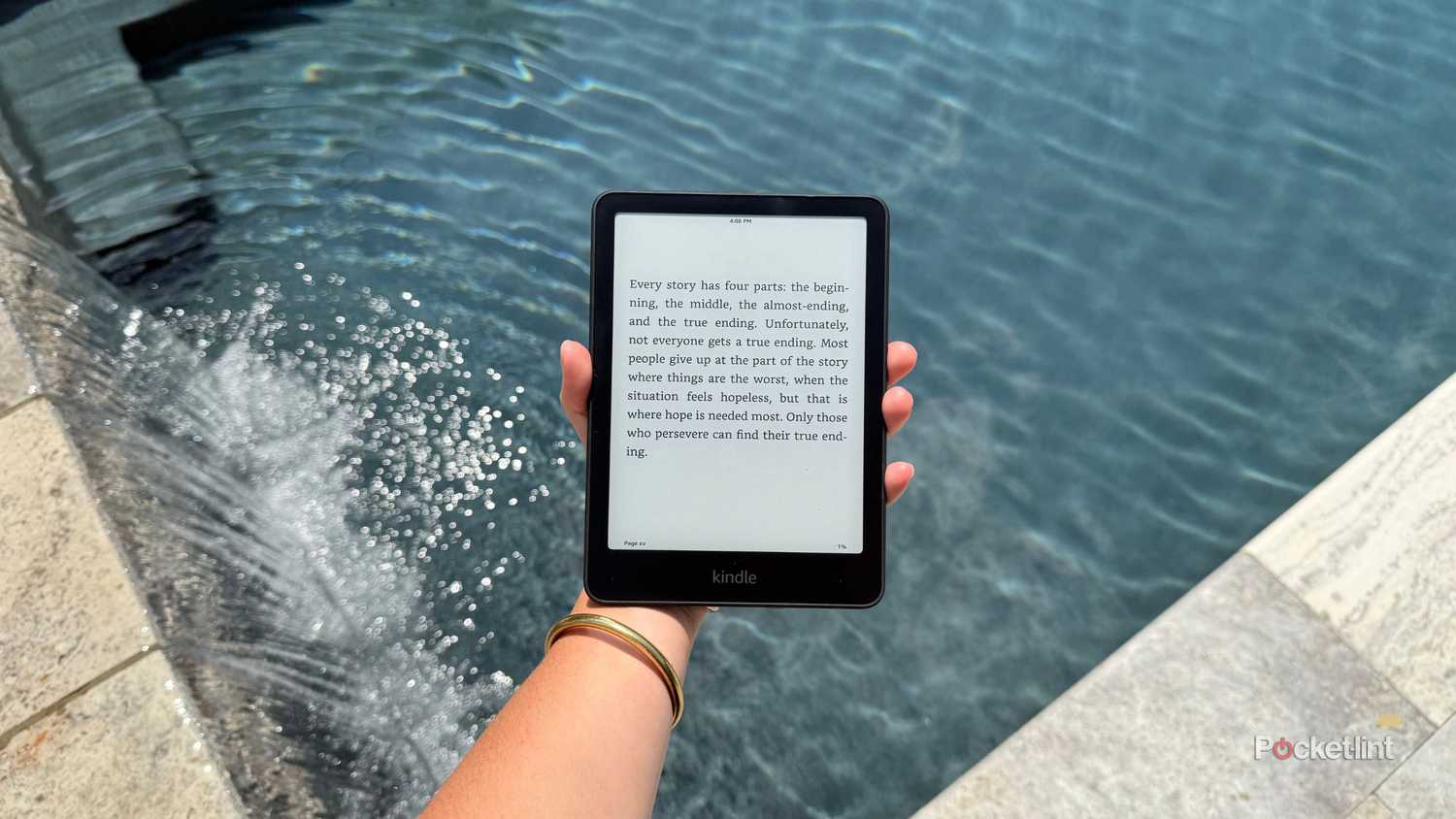 Holding a Kindle Paperwhite over the pool. 