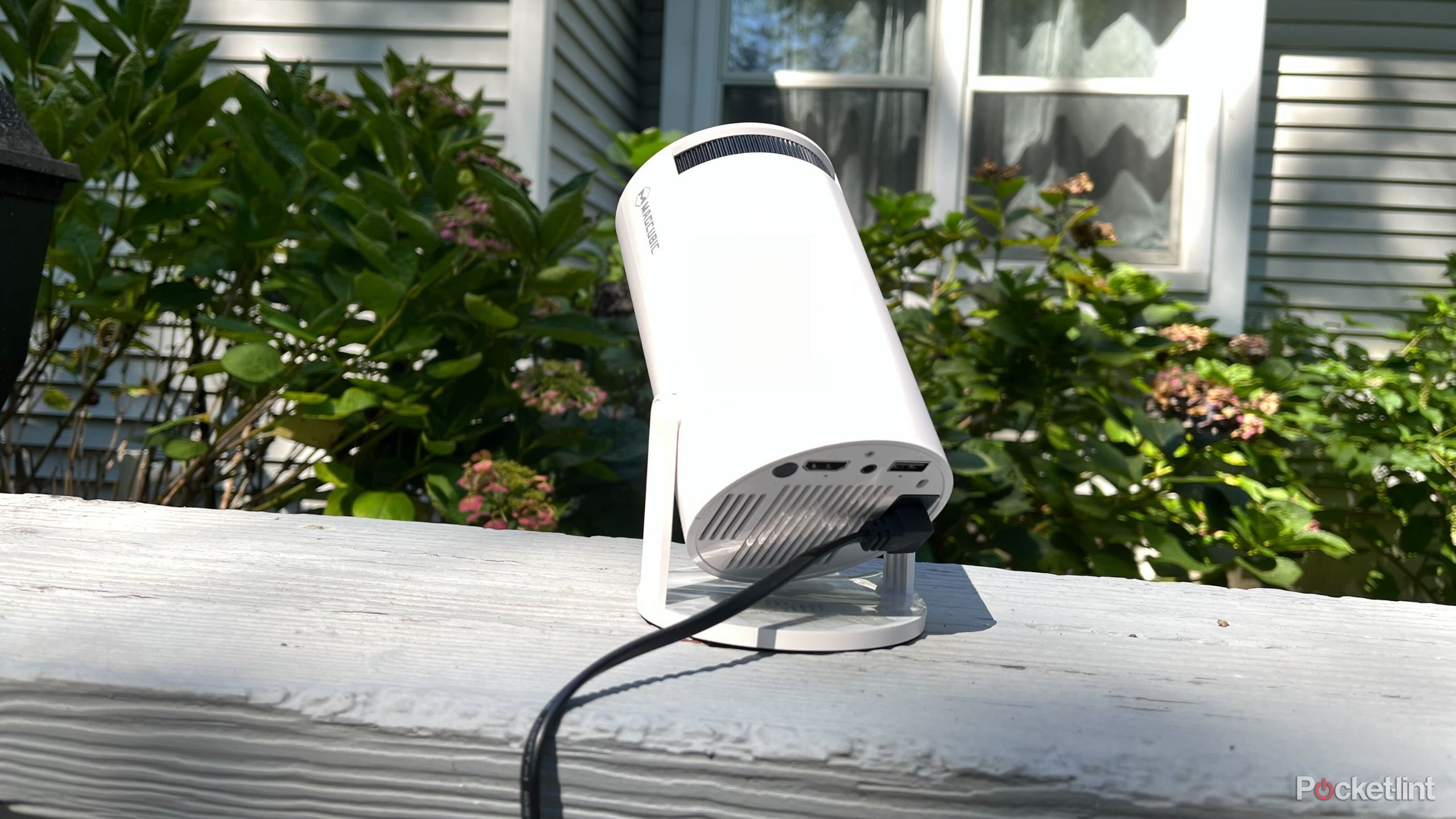 A projector sitting on a bannister outside. 