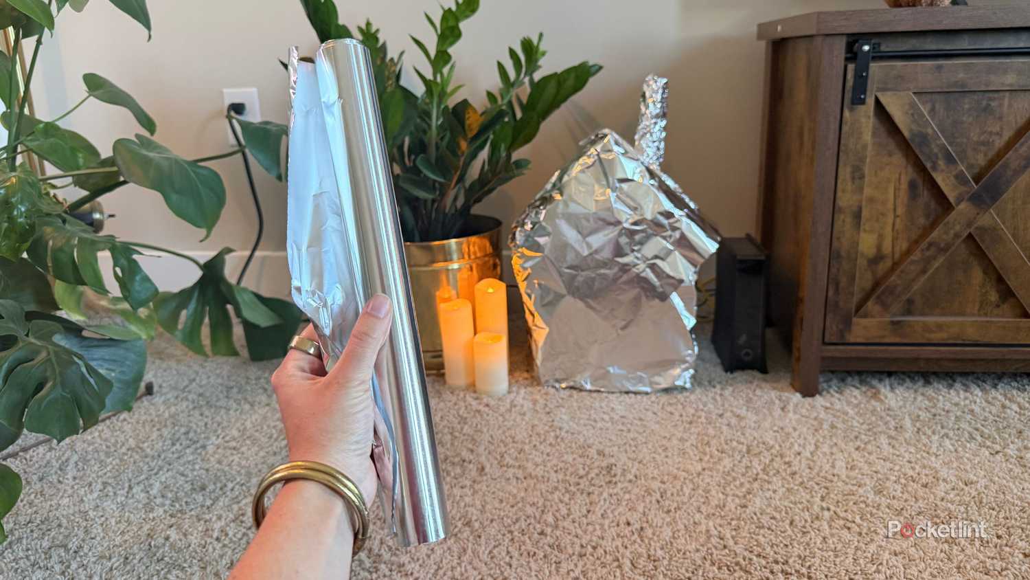Holding a roll of aluminum foil in front of a house. 