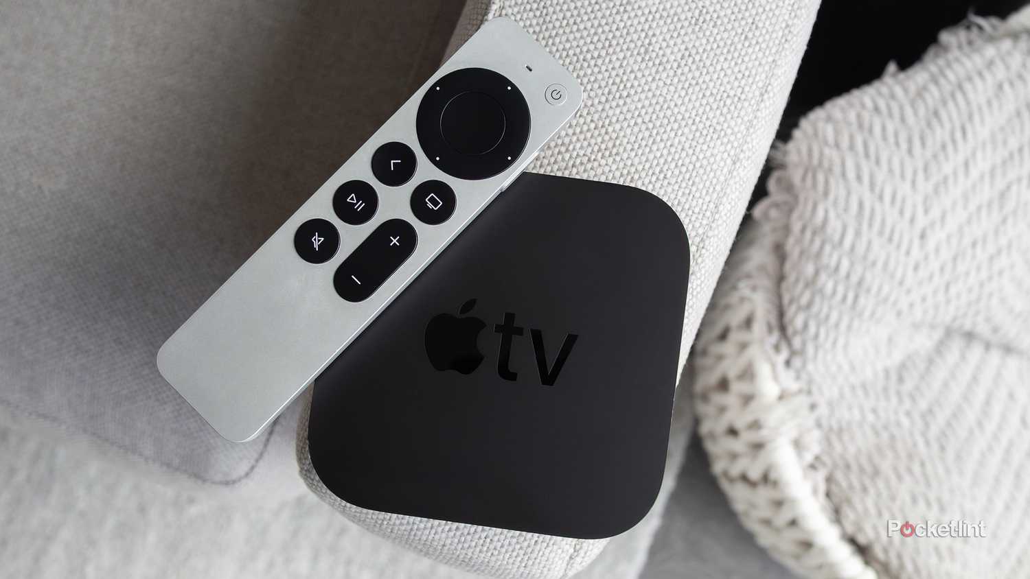 The Apple TV 4K and the Siri Remote sitting on a couch arm