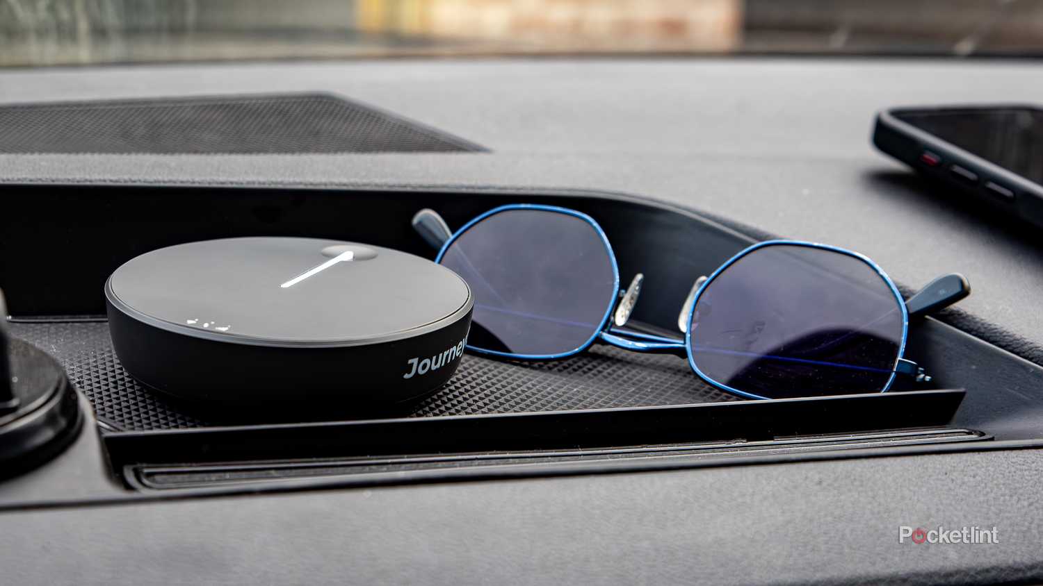A still photo of the Travlfi JourneyGo placed in the dash tray of a car. 