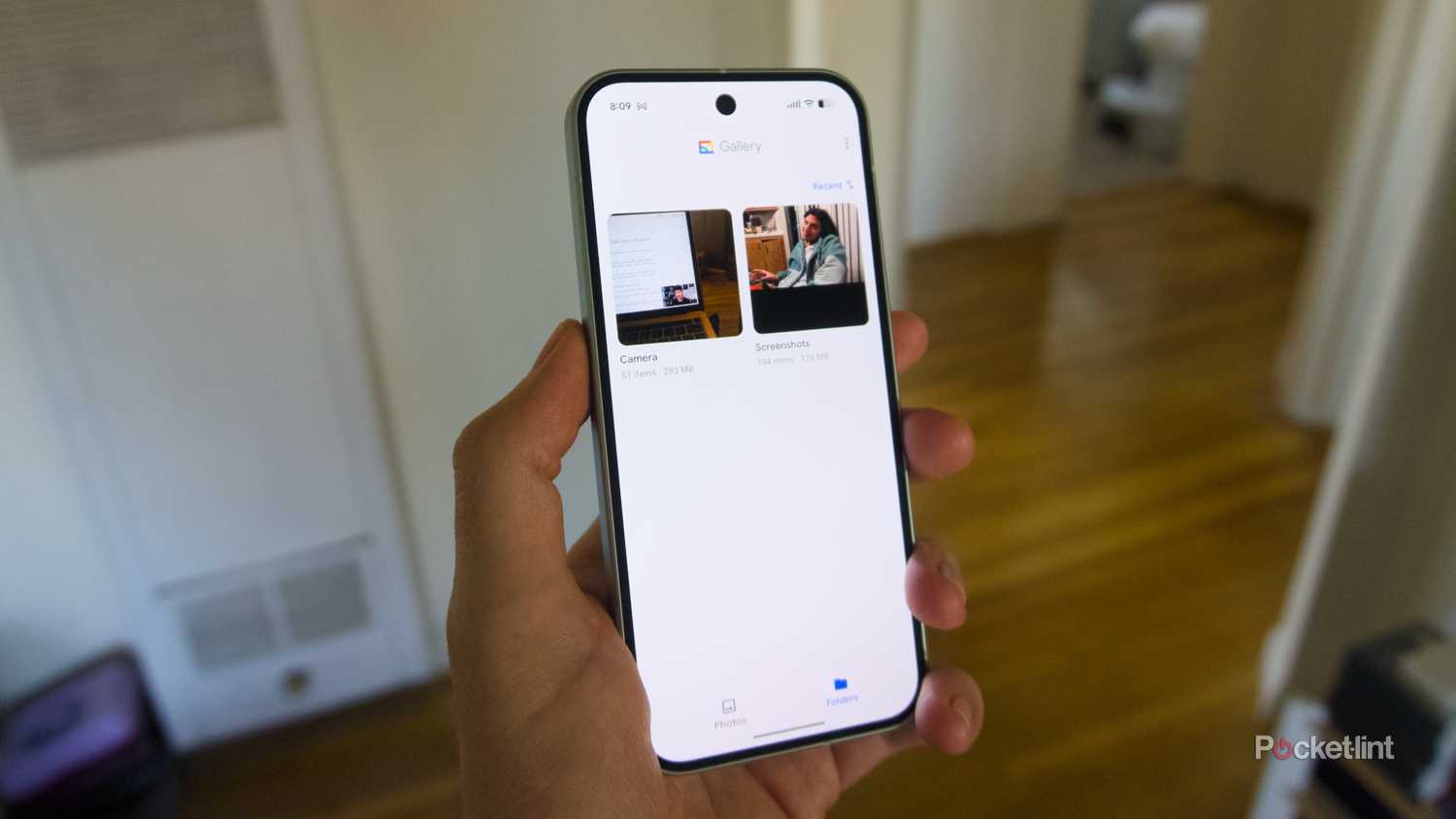 A hand holding a Pixel 9 displaying the folders section of the Google Gallery app.