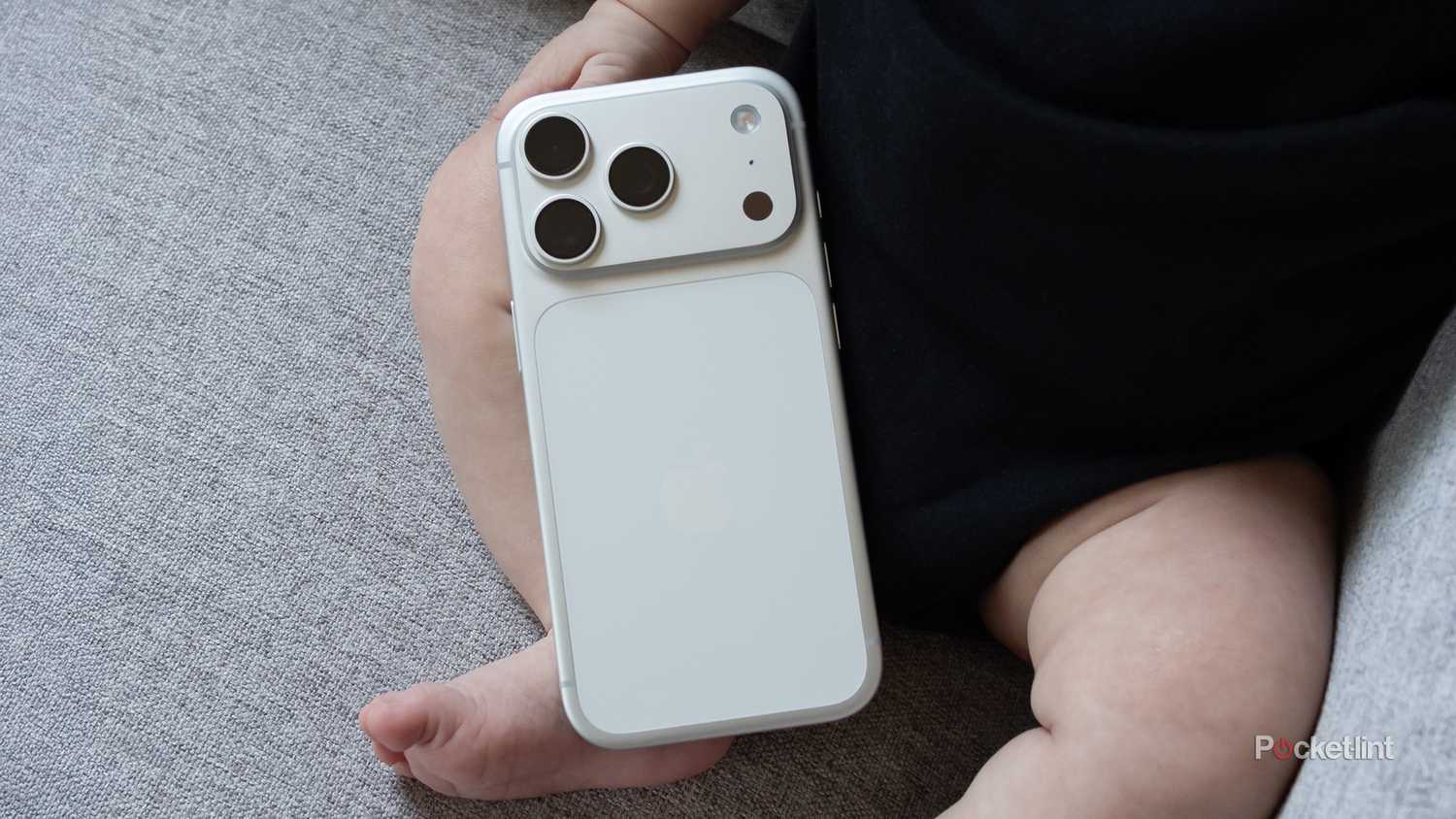 The iPhone 17 Pro sitting on a baby's leg .