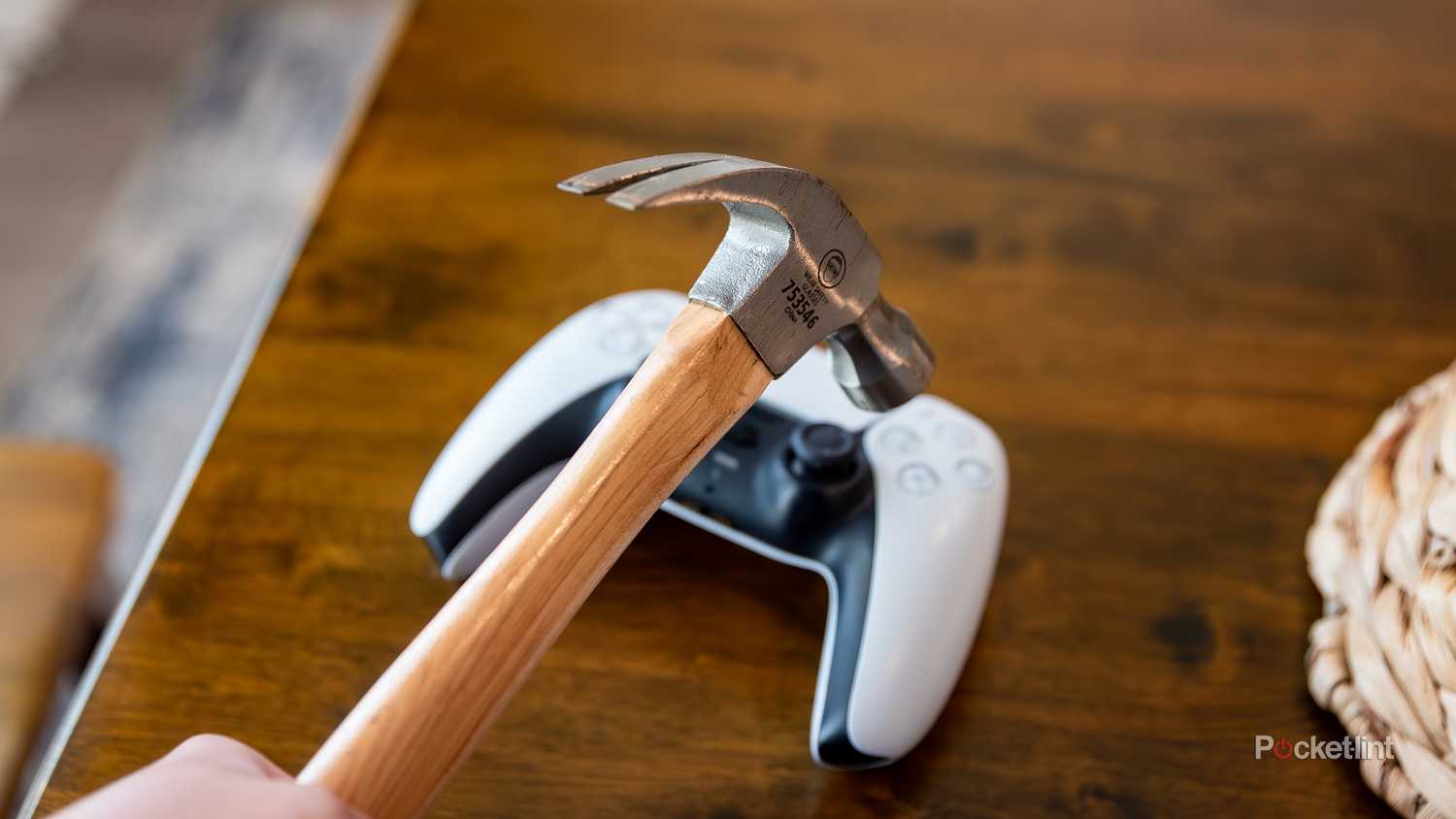 A still photo of a hammer hovering over a PlayStation 5 controller. 