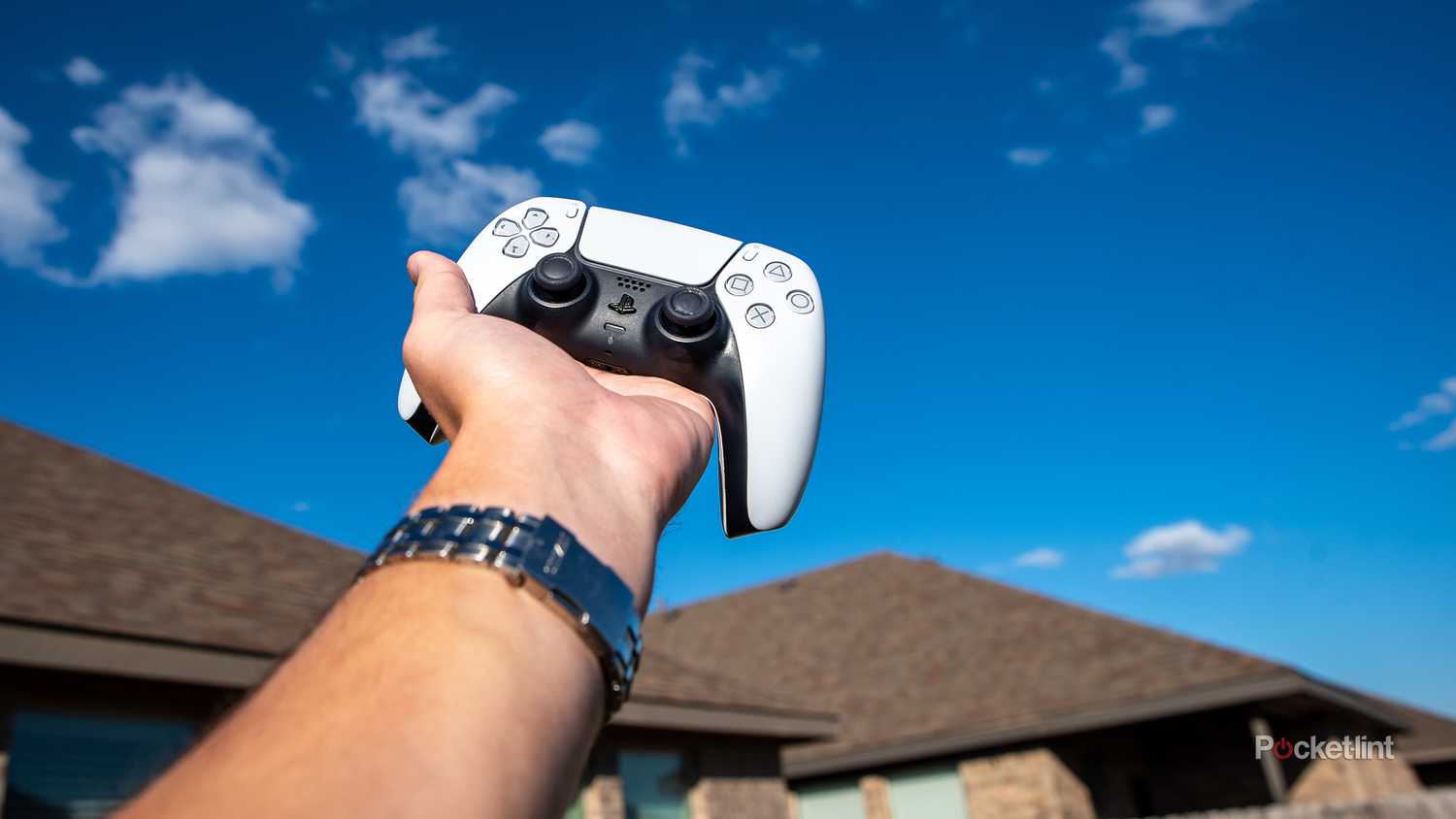 A still photo of an arm holding a PlayStation 5 controller to the sky. 