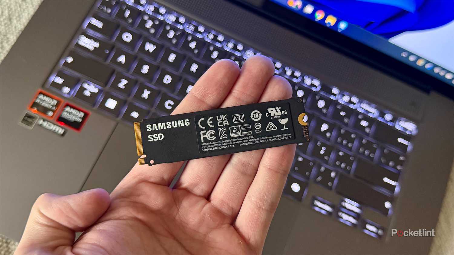Person holding SSD in front of laptop.
