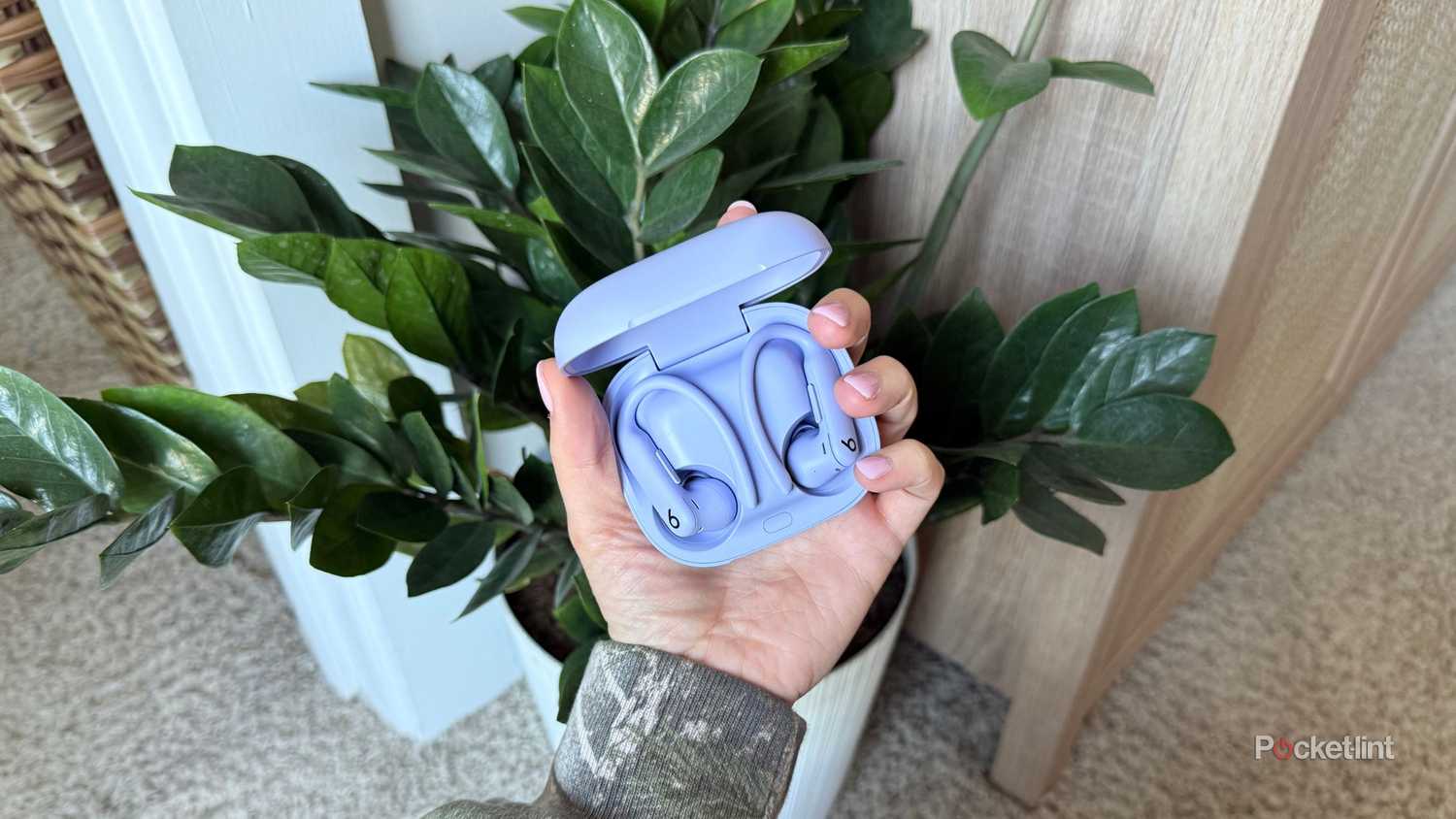 A hand holding the purple Powerbeats Pro 2. 