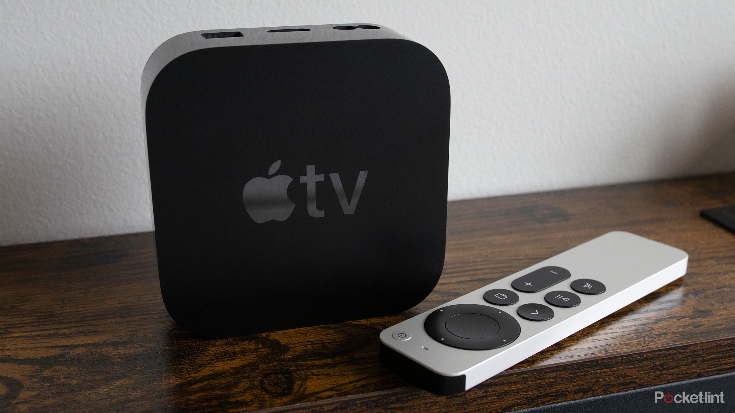 The Apple TV 4K sitting on a shelf with the Siri Remote 