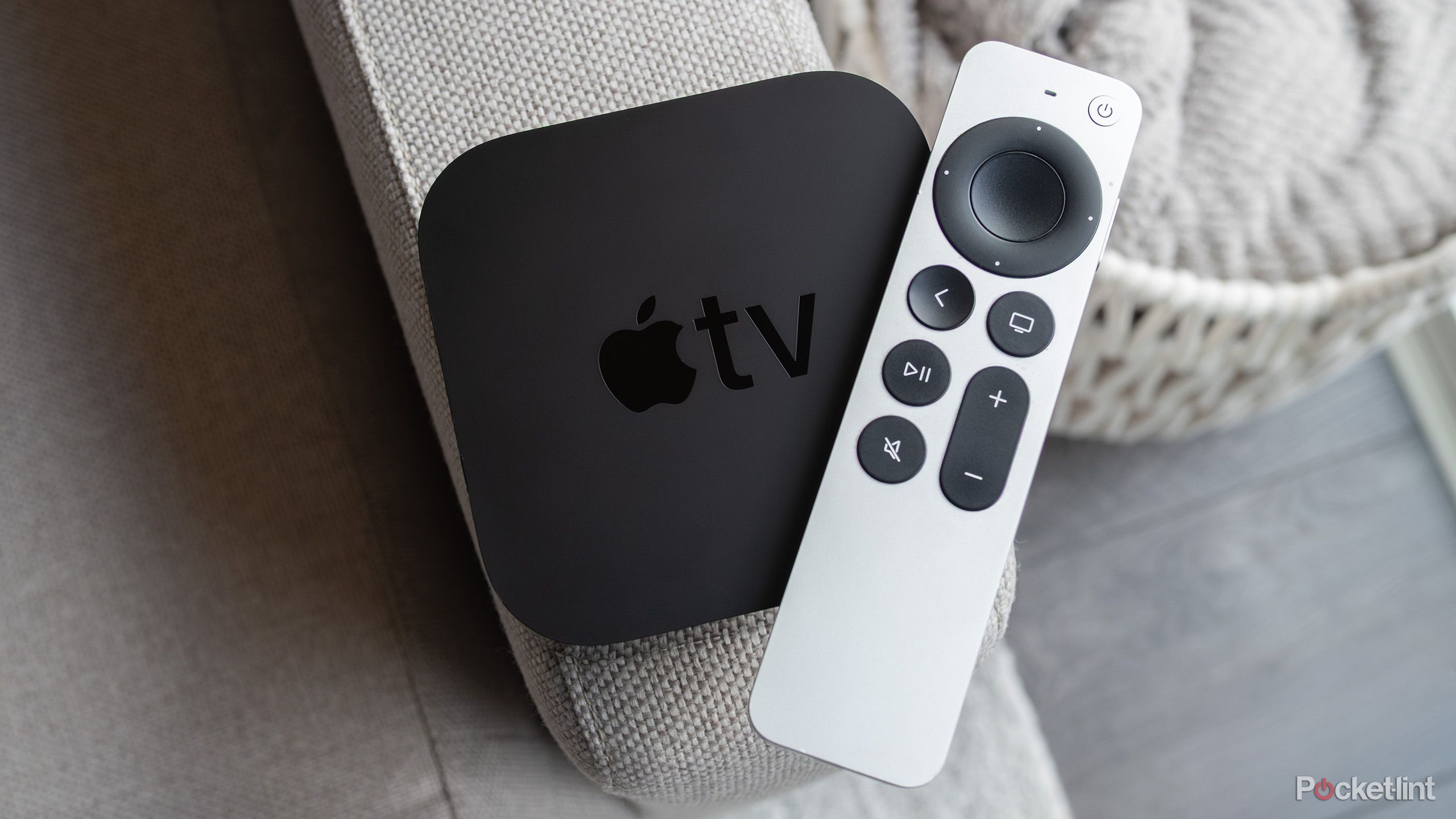 The Apple TV 4K (2021) and the Siri Remote sitting on a couch arm