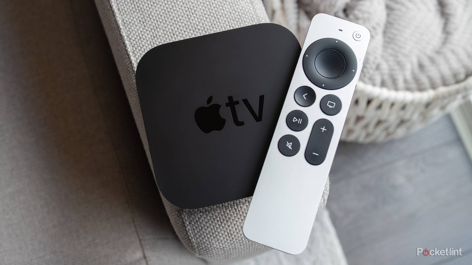 The Apple TV 4K (2021) and the Siri Remote sitting on a couch arm