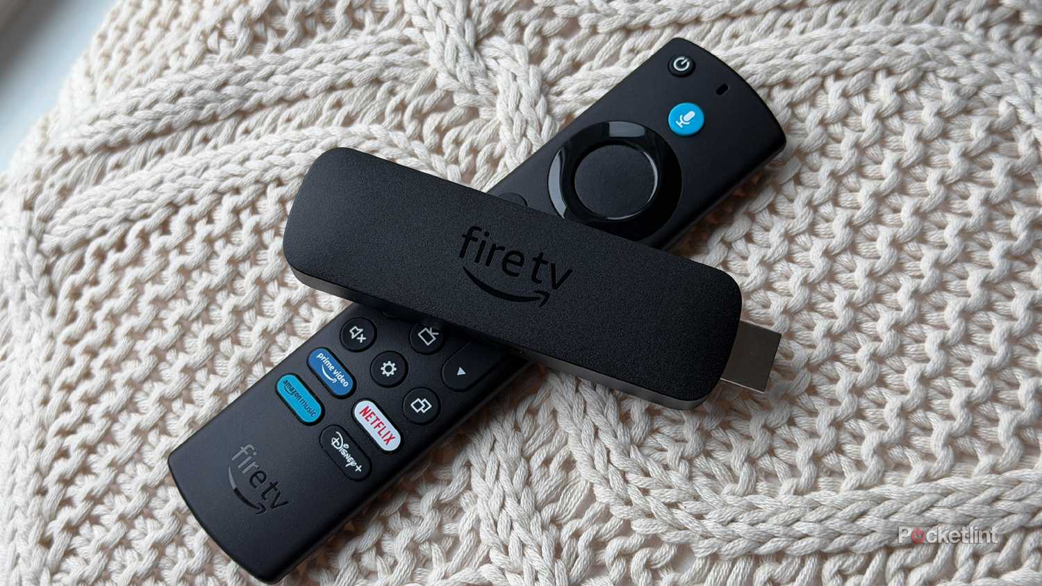 Fire TV Stick and Fire TV remote on knit pillow.