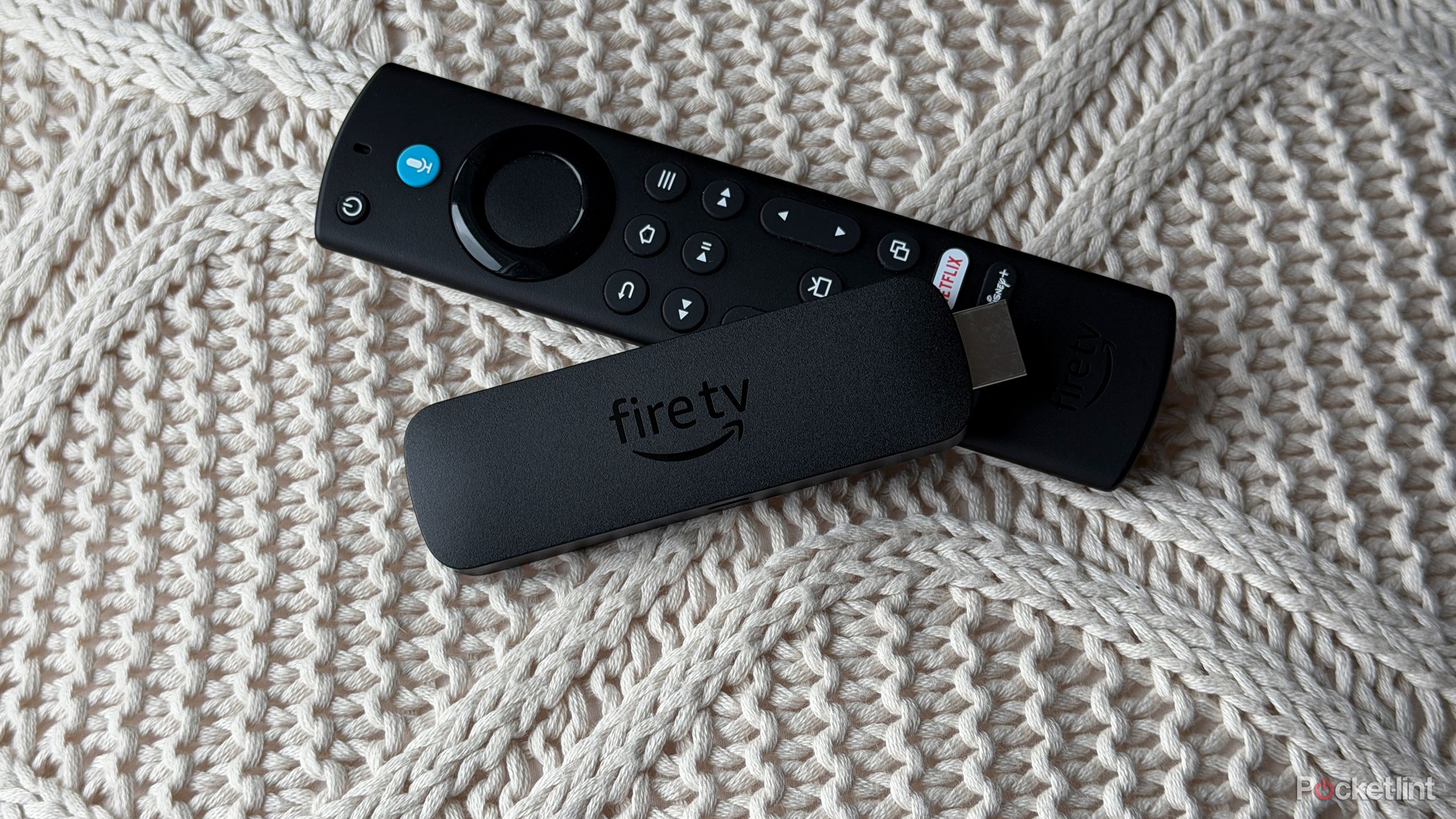 Fire TV Stick and remote on knitted pillow.