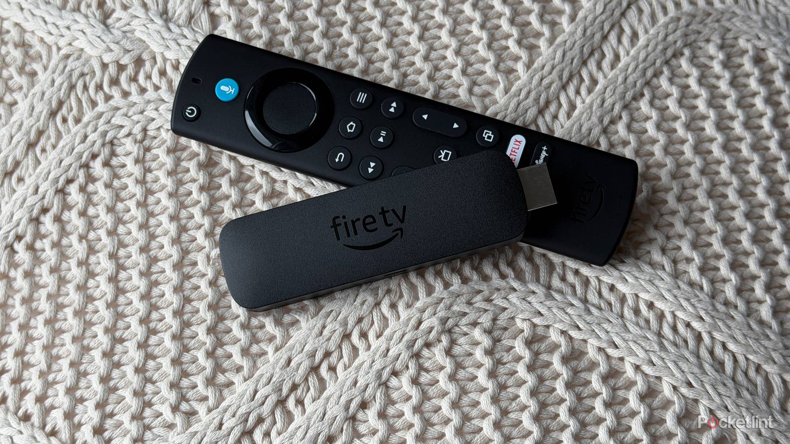 Fire TV Stick and remote on knitted pillow.
