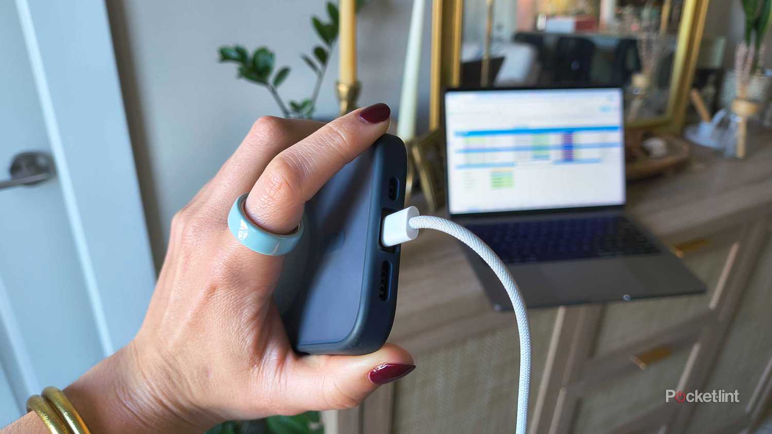 A hand holding an iPhone 16 Pro plugged in. 