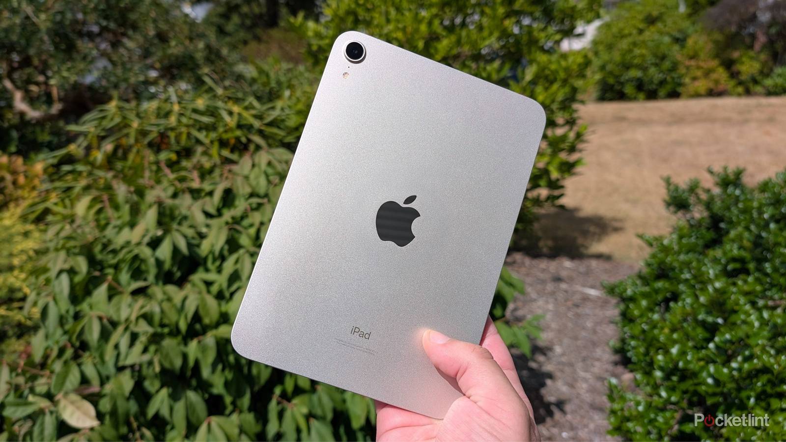 An iPad mini being held up in the air.