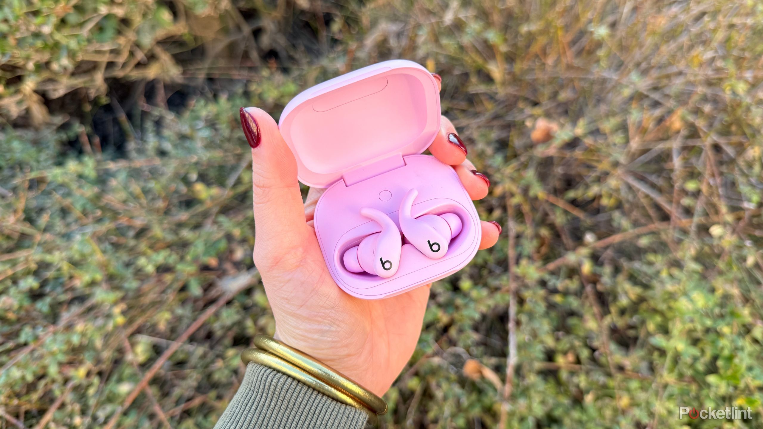 Holding the Pink Powerbeats Fit. 