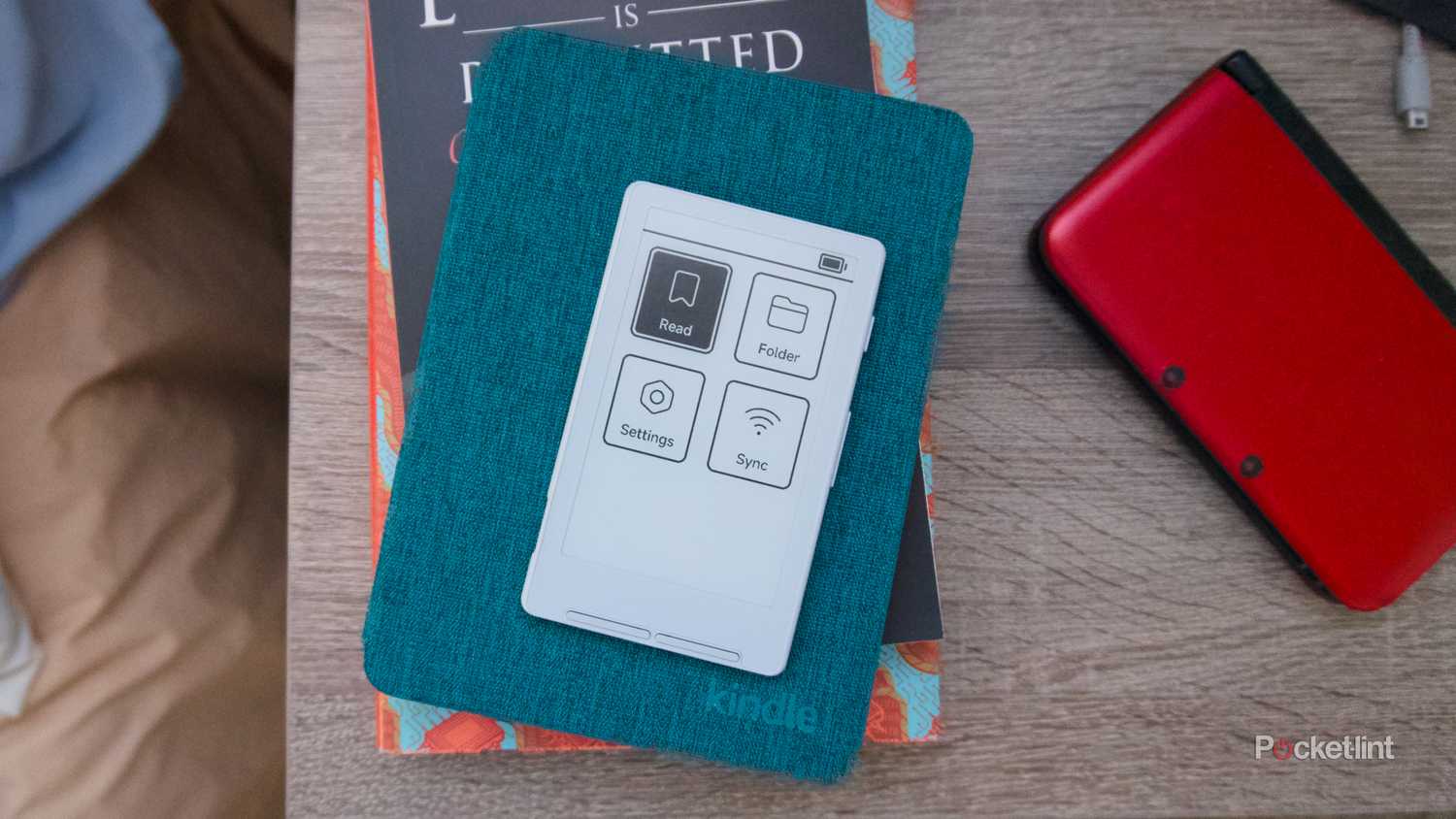 An Xteink X4 e-reader laying on a side tablet open to its menu.