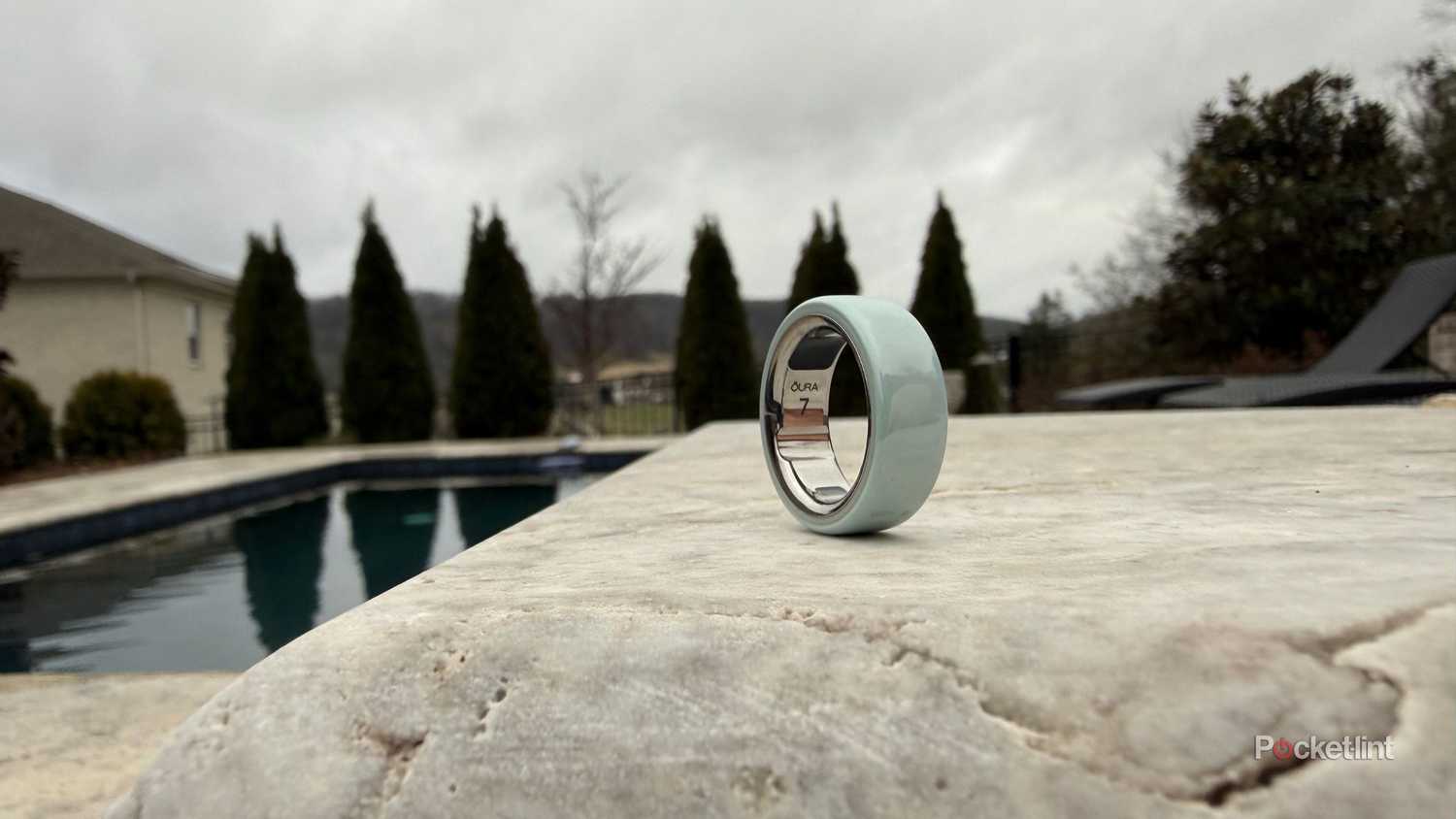 The Oura Ring 4 Ceramic in Tidal on a rocky surface. 