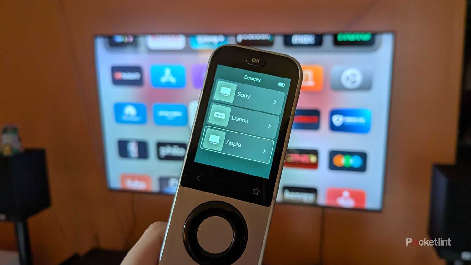 A Sofabaton X2 remote in front of a TV.