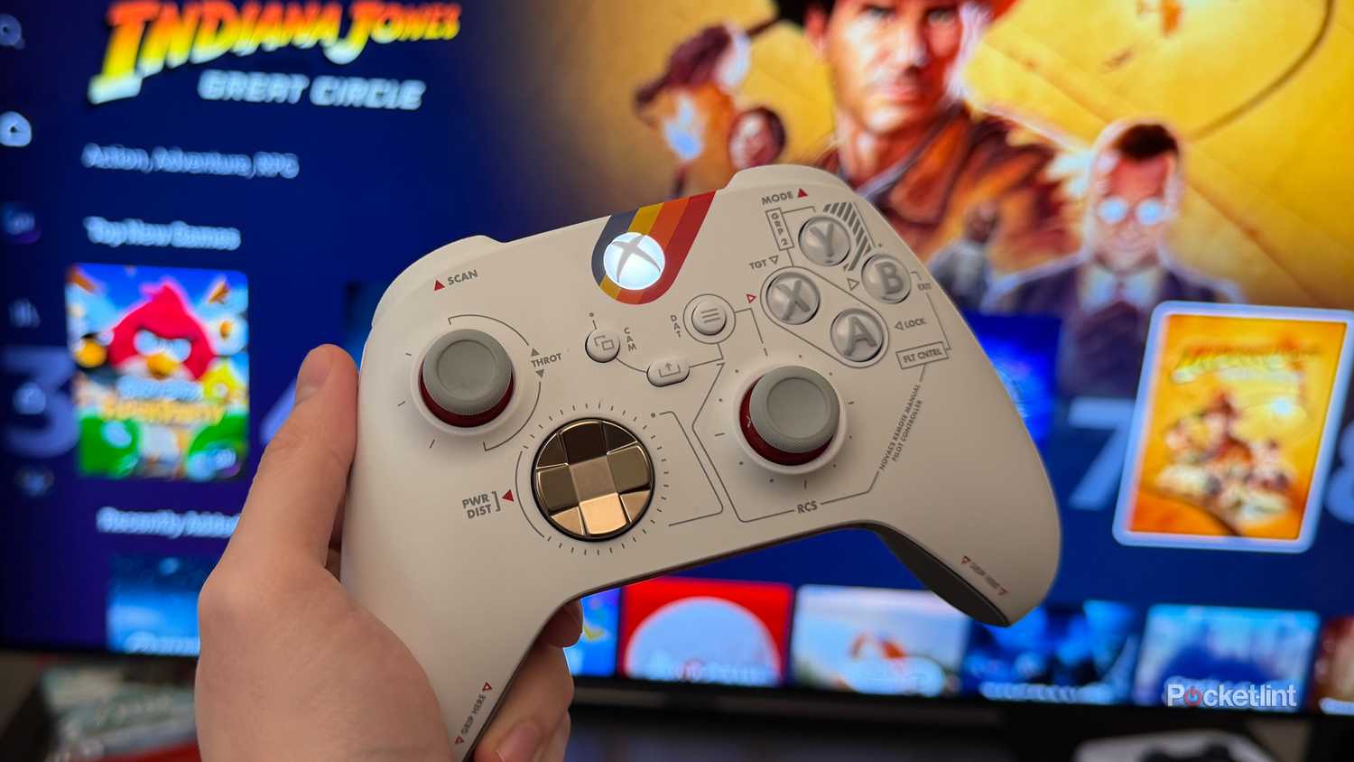 Person holding Xbox controller in front of TV.