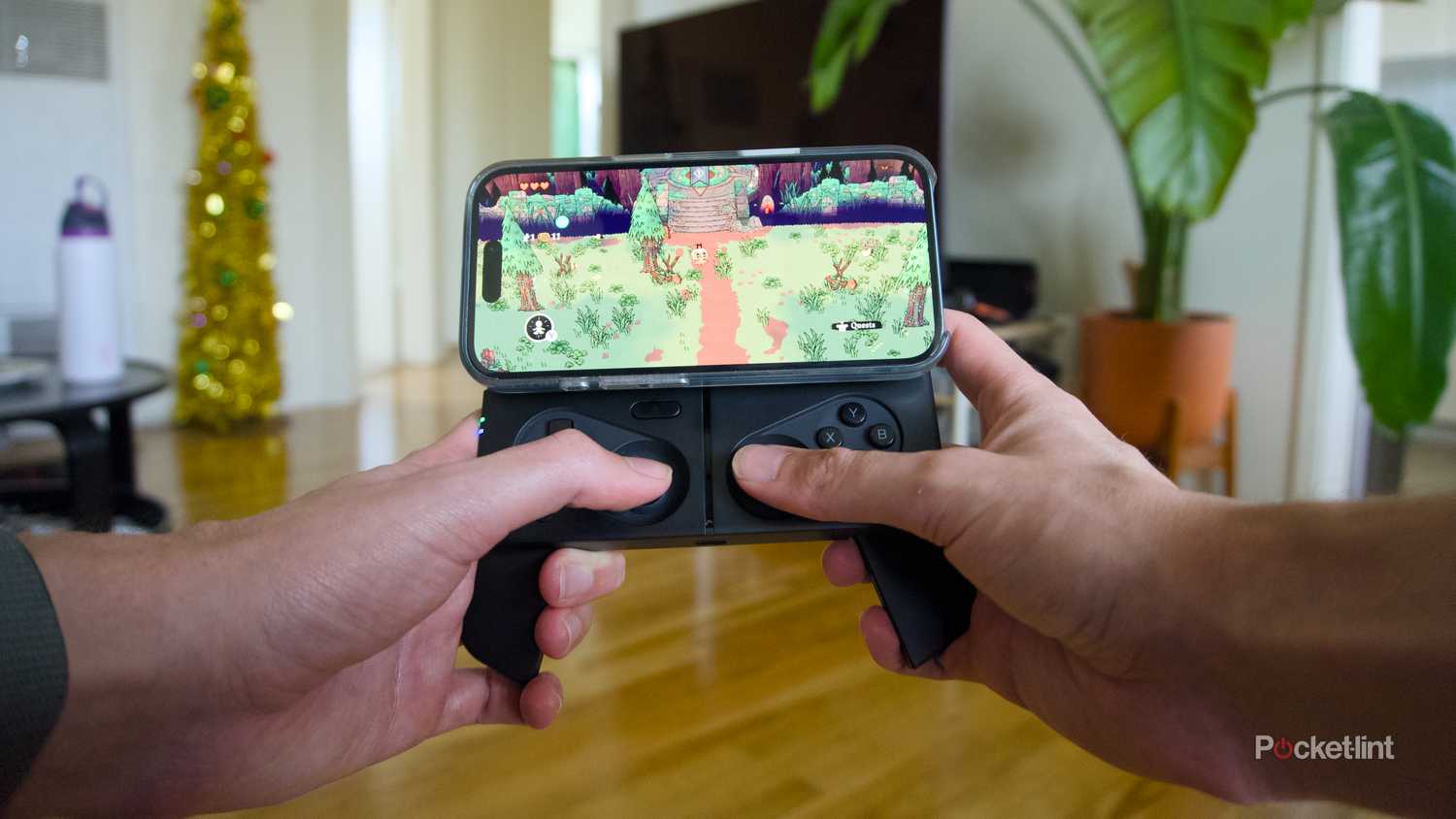An iPhone 16 playing Cult of the Lamb attached to an open MCON controller.
