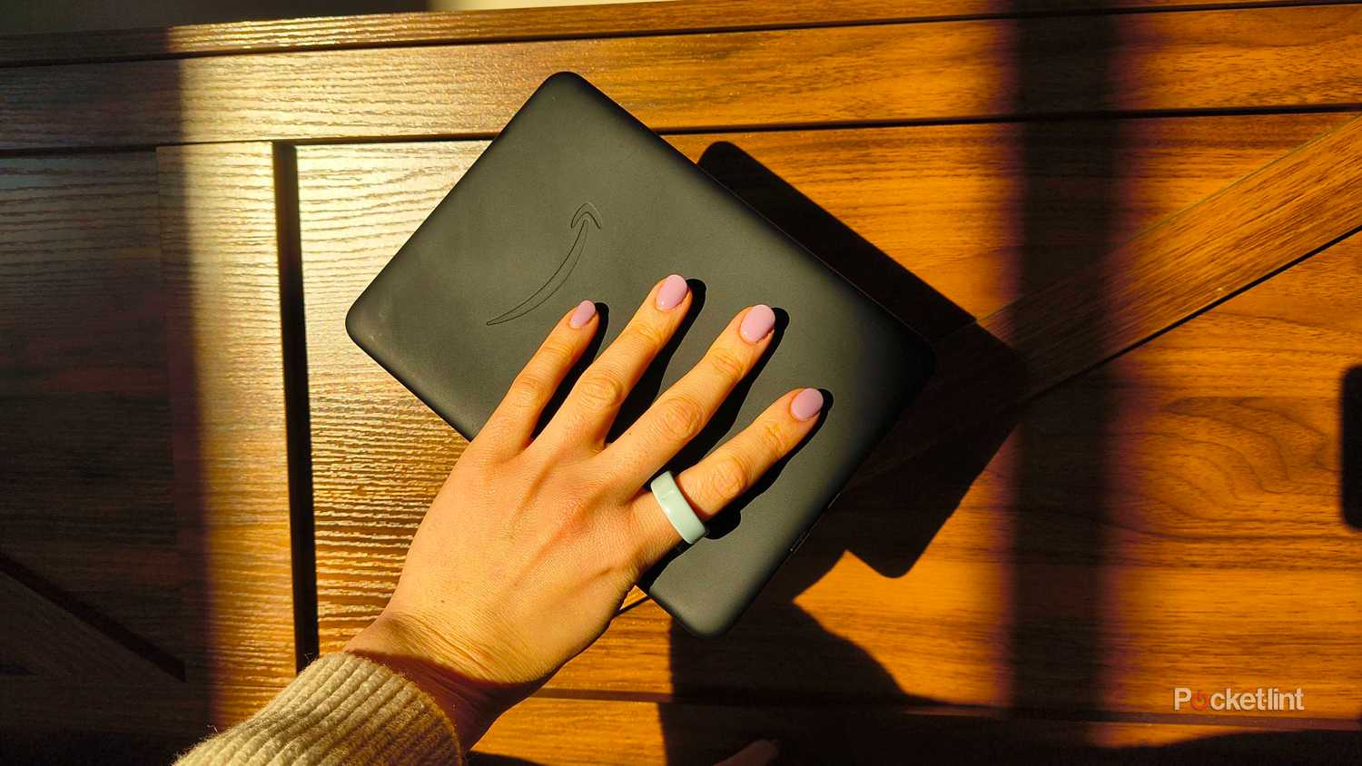 A hand with pink nails holding the Kindle Paperwhite. 