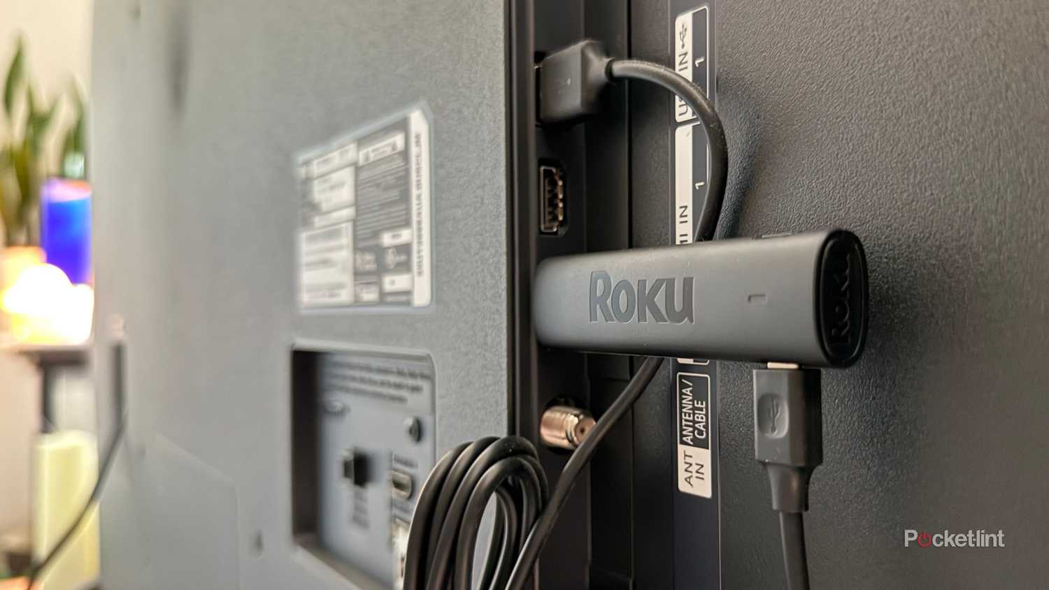 A Roku stick plugged in behind a TV.