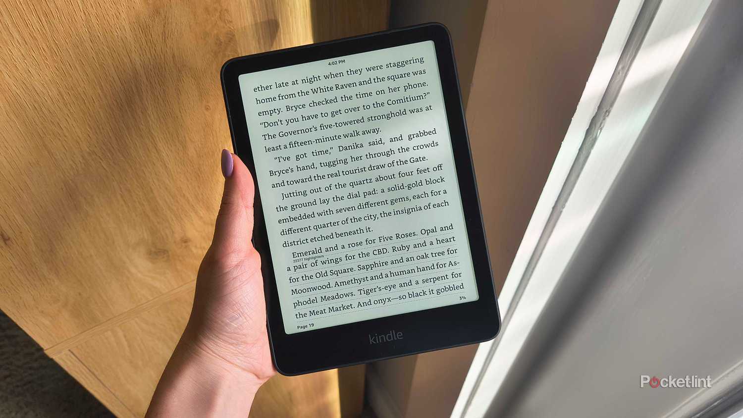 A Kindle beside a window.