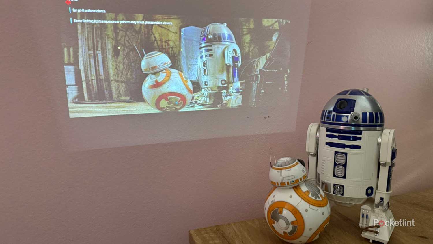 Aurzen Zip Projector palying Star Wars on wall with droids watching.