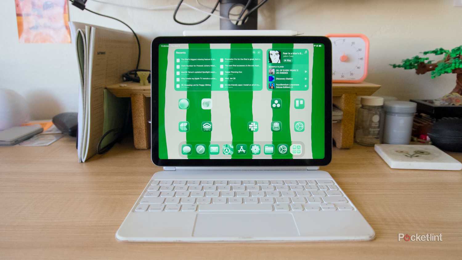 An iPad Air on a white Magic Keyboard showing off a green home screen.