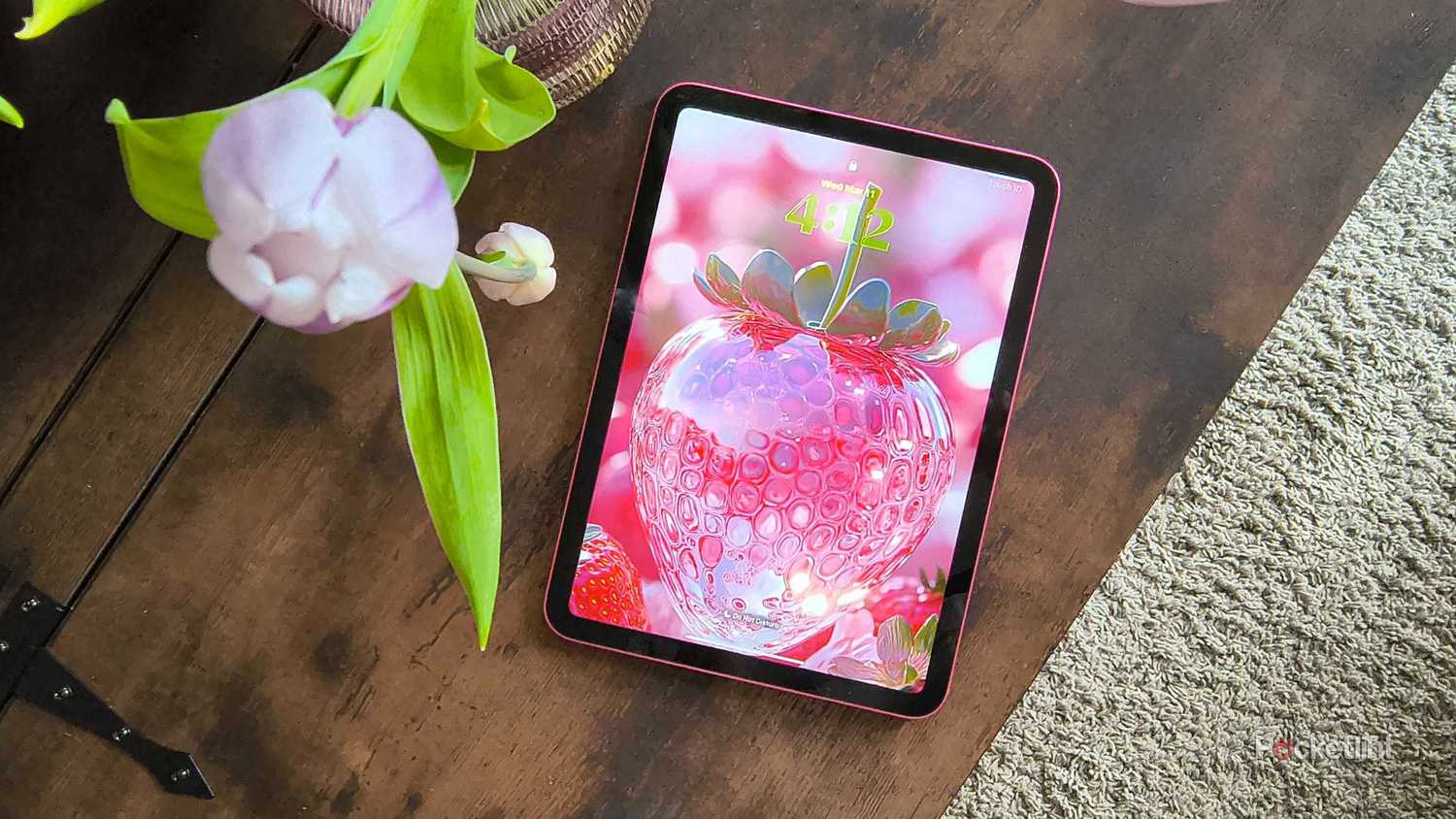 A pink iPad with a glass strawberry. 