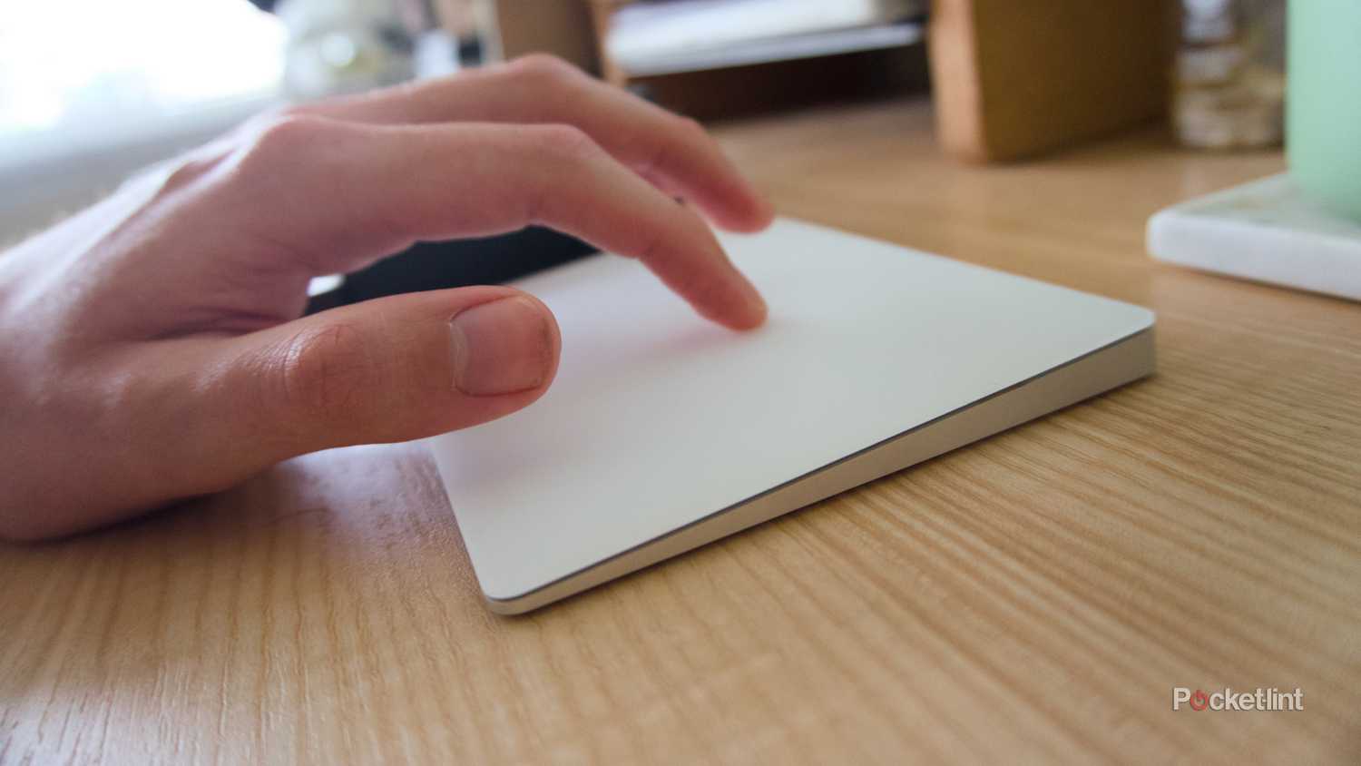 A hand swiping on a white Magic Trackpad.