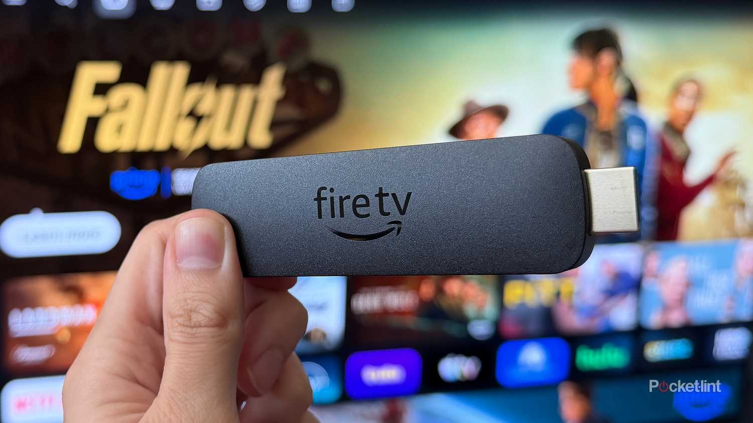 Person holding Fire TV Stick 4K Max in front of TV.