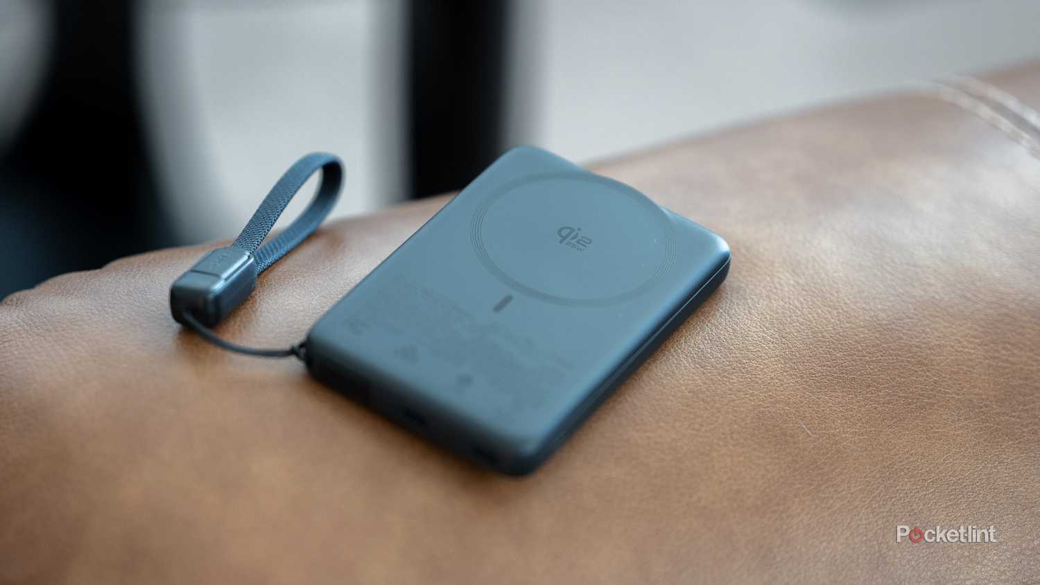 INIU SnapGo Air Power Bank lying flat on leather couch showing Qi2 wireless charging face.