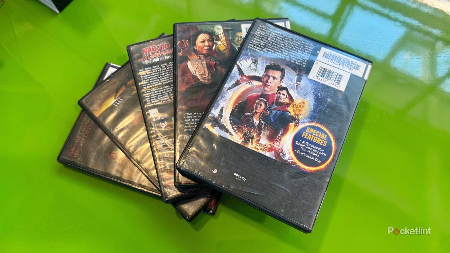 Five DVDs fanned out on a green table at a local library