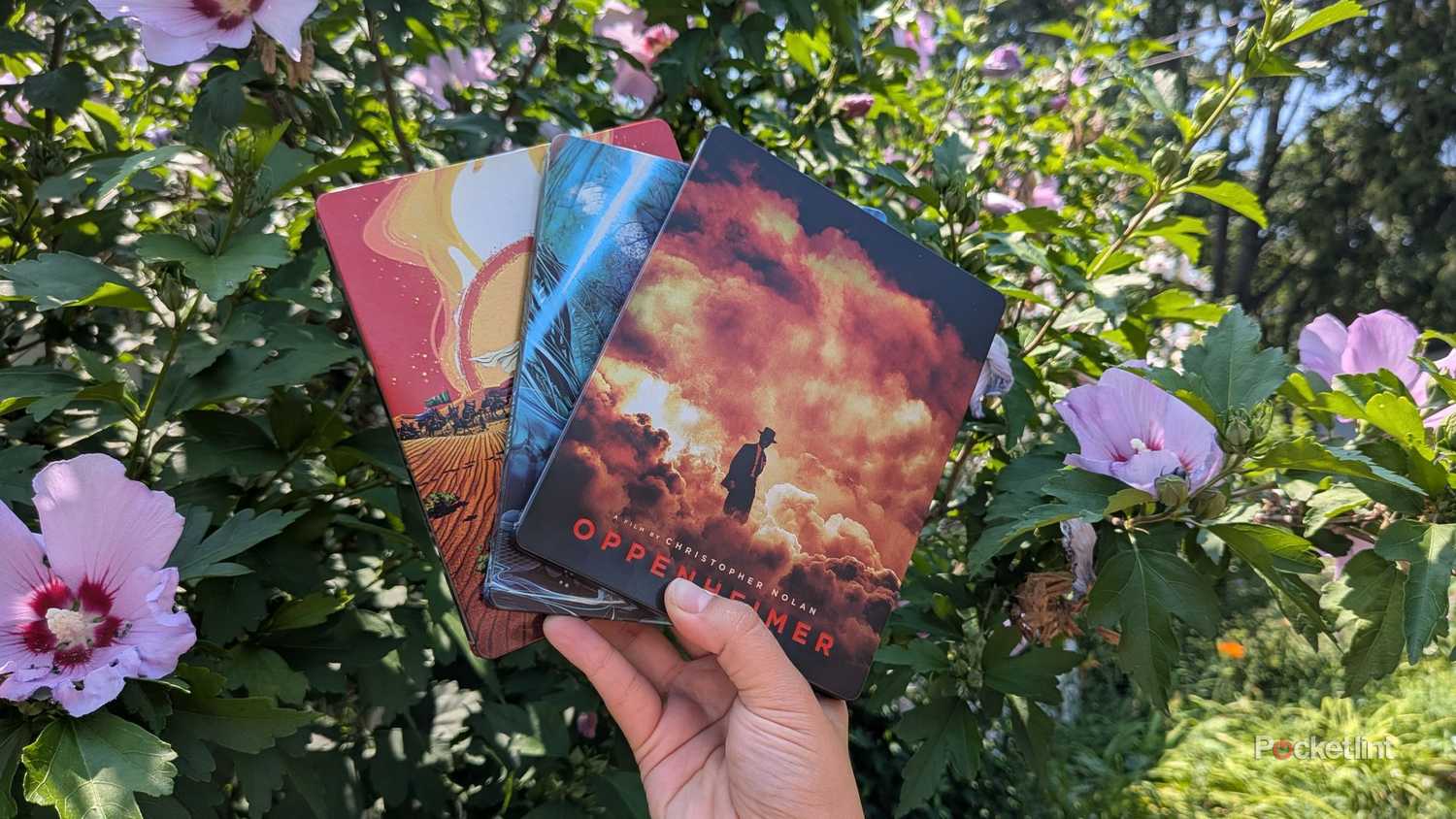 Людина з трьома сталевими книгами на вулиці.