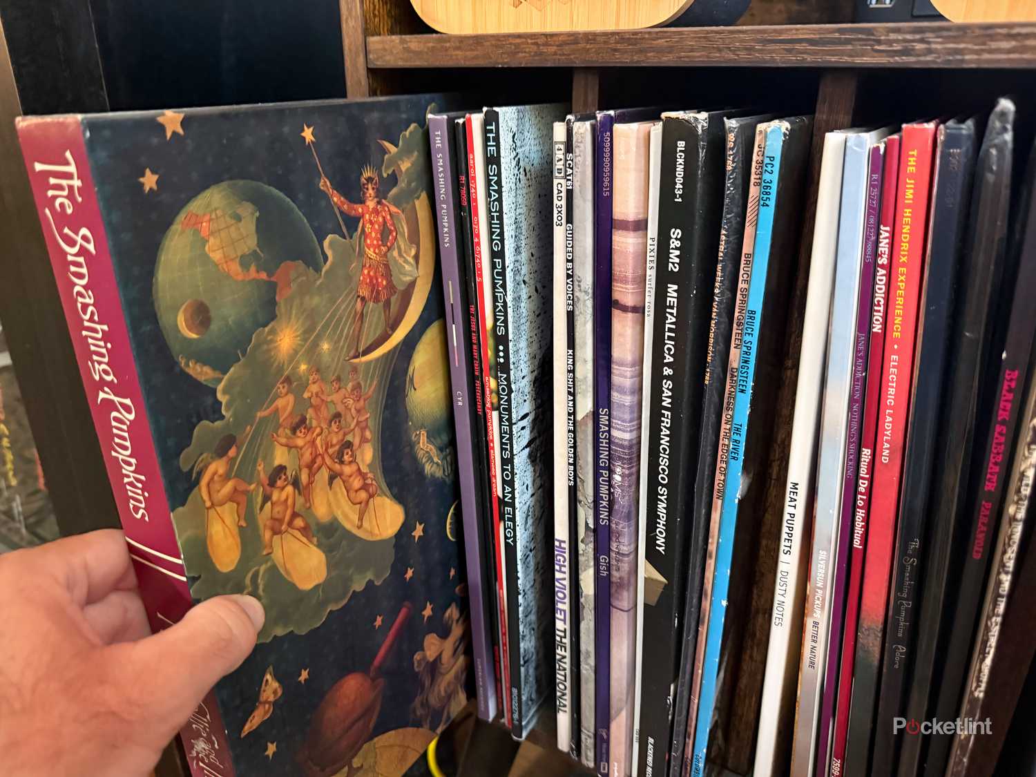 Hand removing vinyl collection of Smashing Pumpkins album from record shelf.