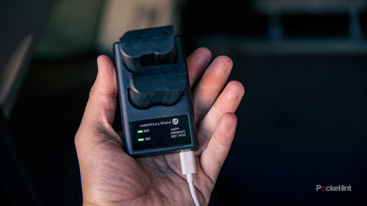 A still photo of a pair of camera batteries being charged by a vehicular USB-C port.