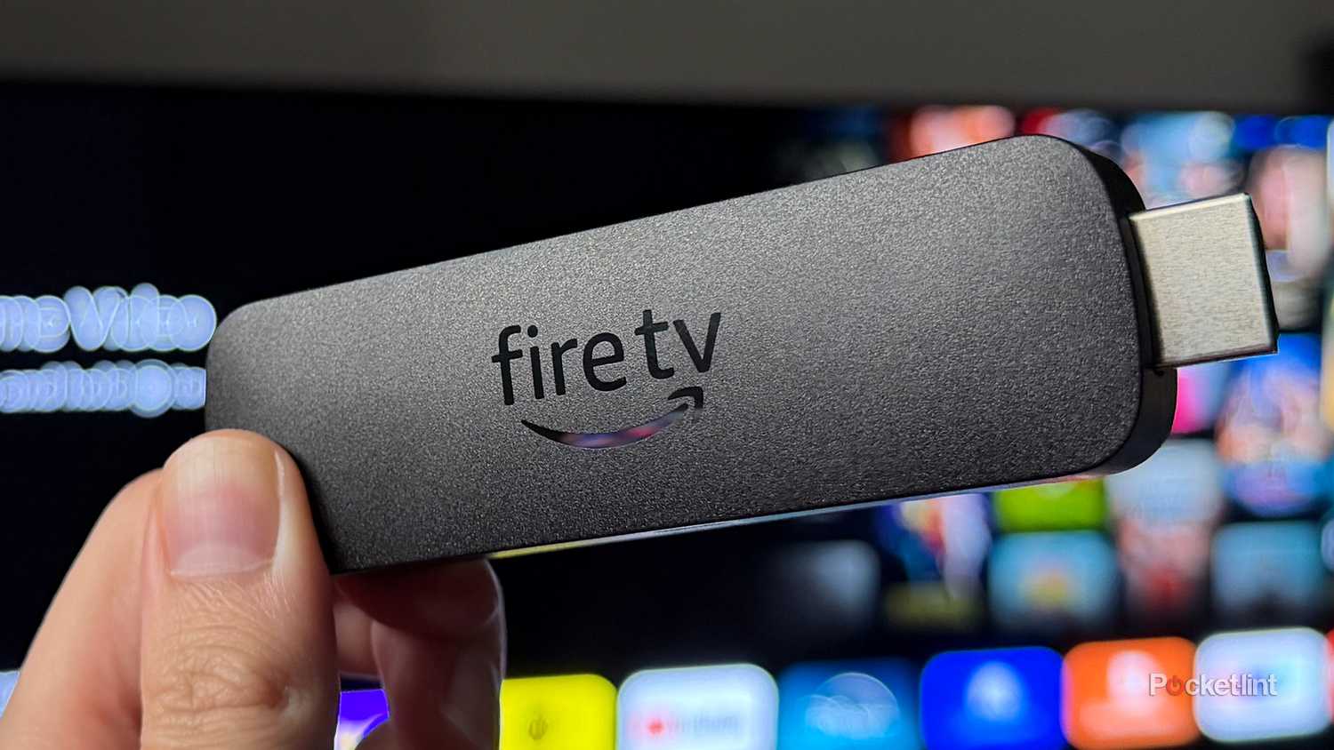 Person holding Fire TV Stick 4K Max in front of TV.